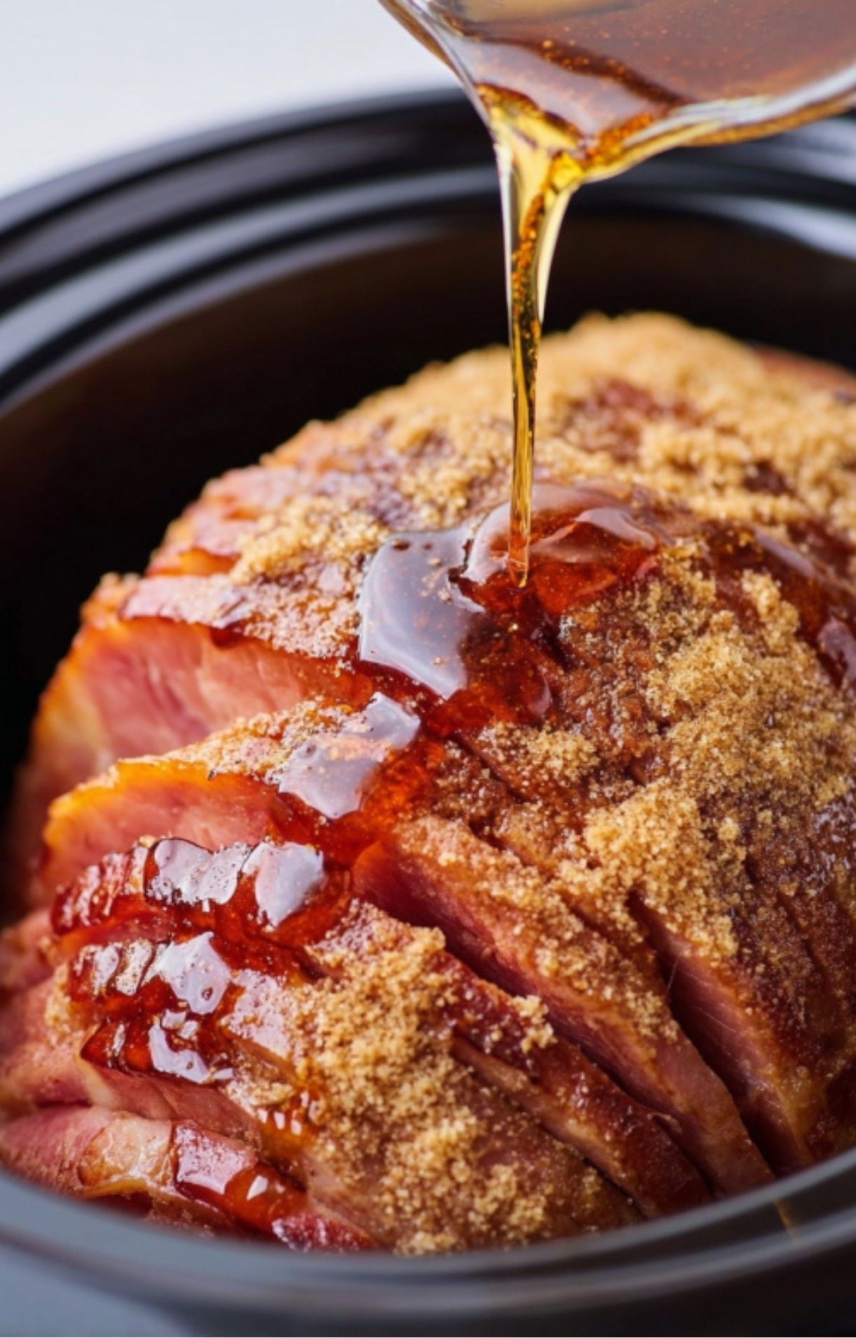 Maple pineapple glaze being poured over spiral ham in a slow cooker for a sweet, sticky finish.