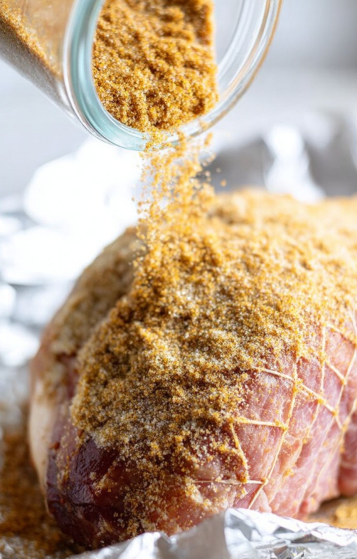 Coating ham with brown sugar spice rub before smoking