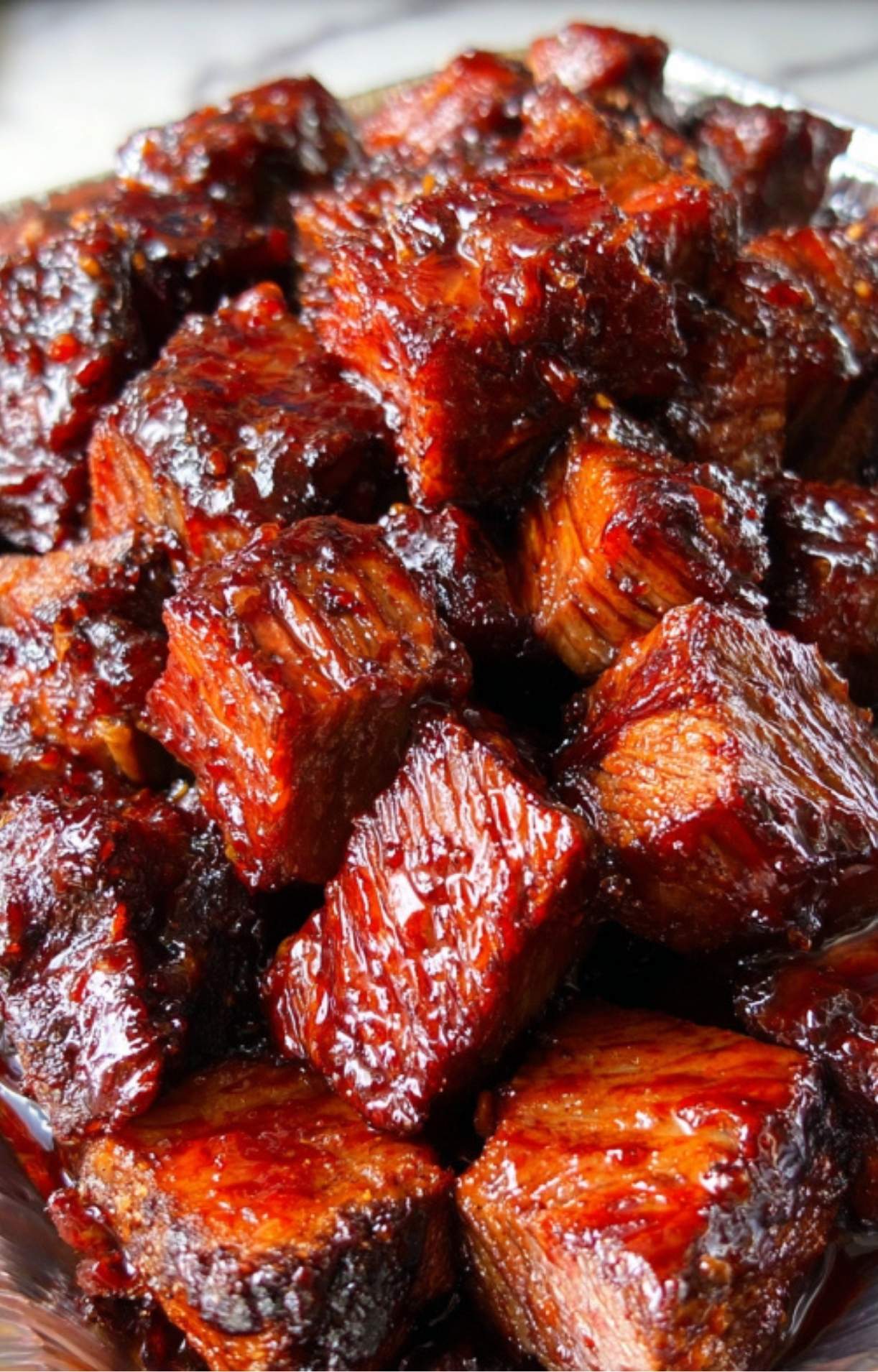 A close-up shot of beef cubes thoroughly coated in a sticky, shiny BBQ glaze after further cooking.