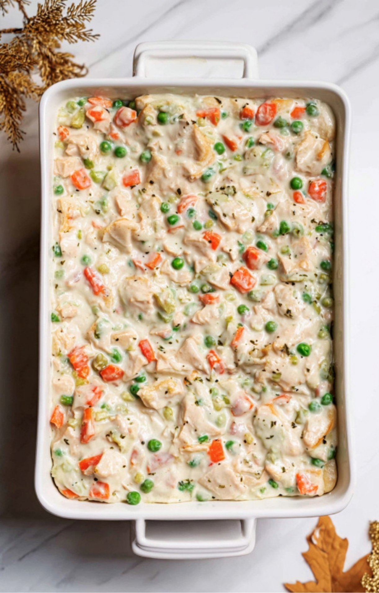 The completed turkey and vegetable filling spread evenly into a white rectangular baking dish.