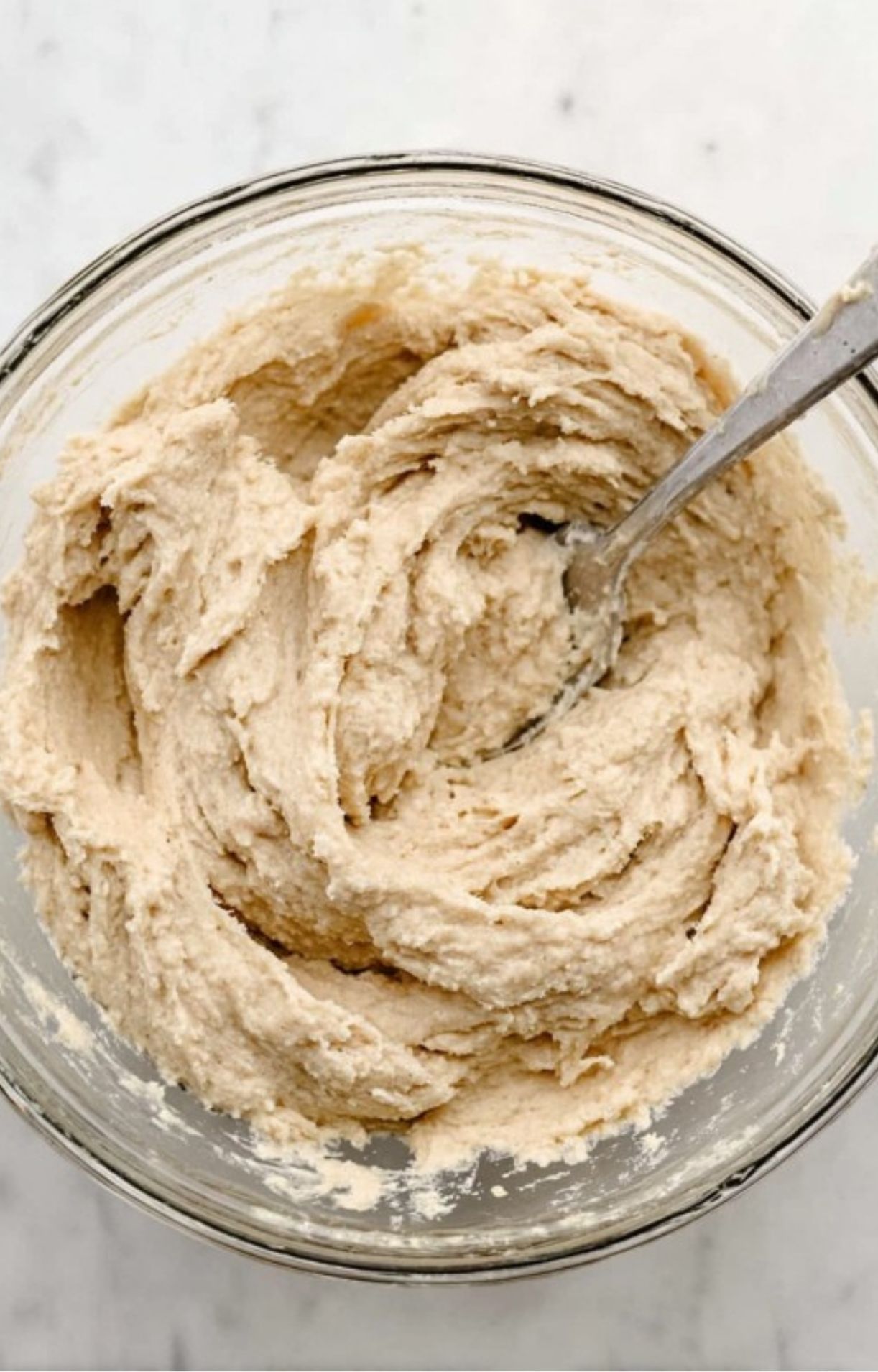 A close-up of thick, well-mixed biscuit dough in a glass bowl, ready to be dropped onto the turkey pot pie filling.