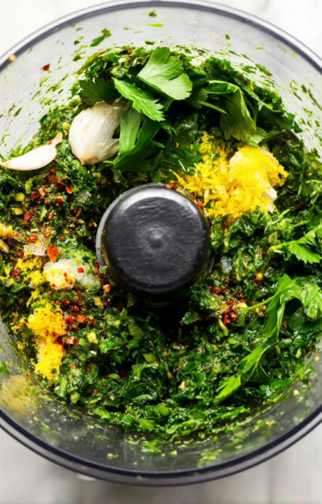 Parsley, cilantro, garlic, lemon zest, and spices in a food processor for making chimichurri sauce