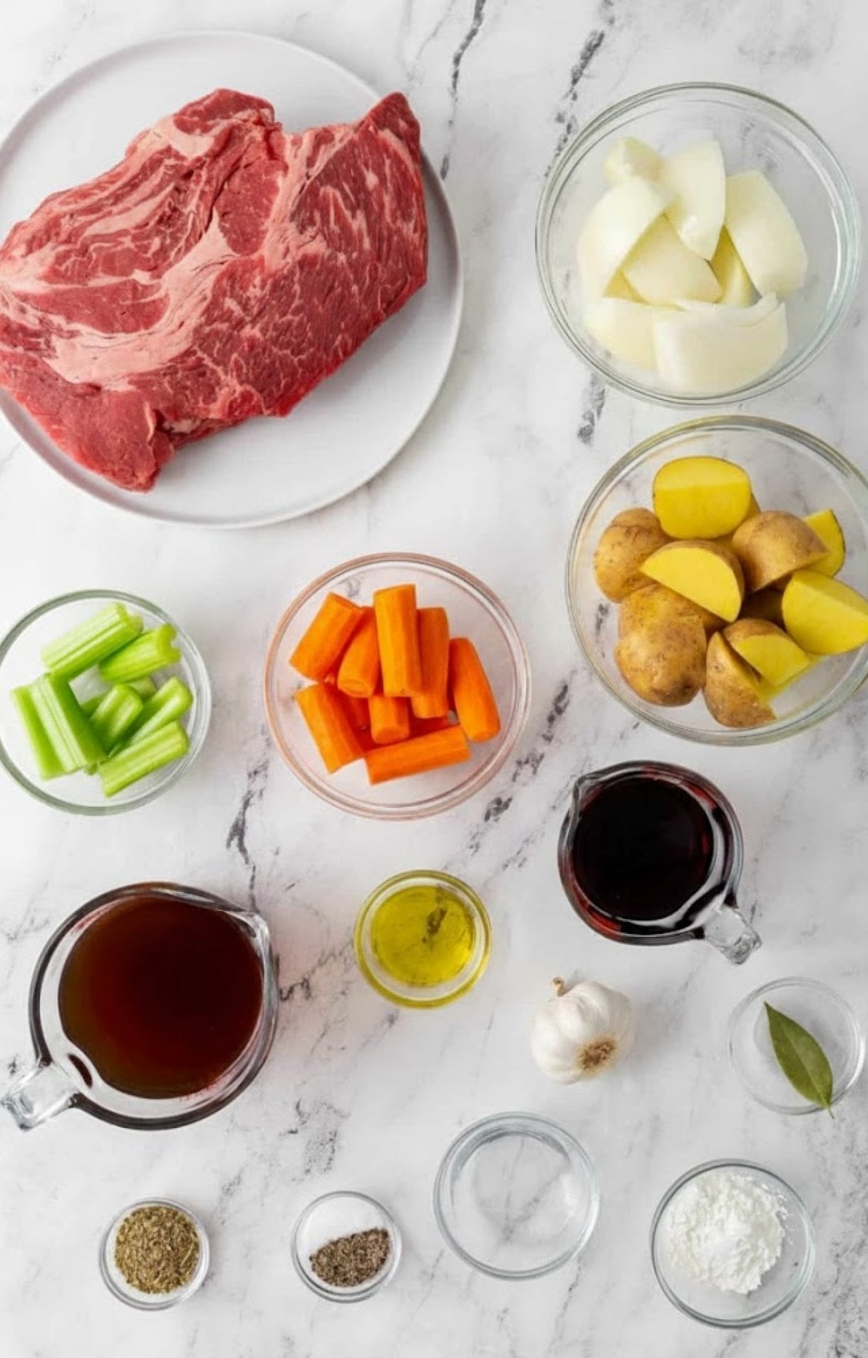 showing a raw beef chuck roast, chopped potatoes, carrots, celery, onions, beef broth, red wine, garlic, and spices.