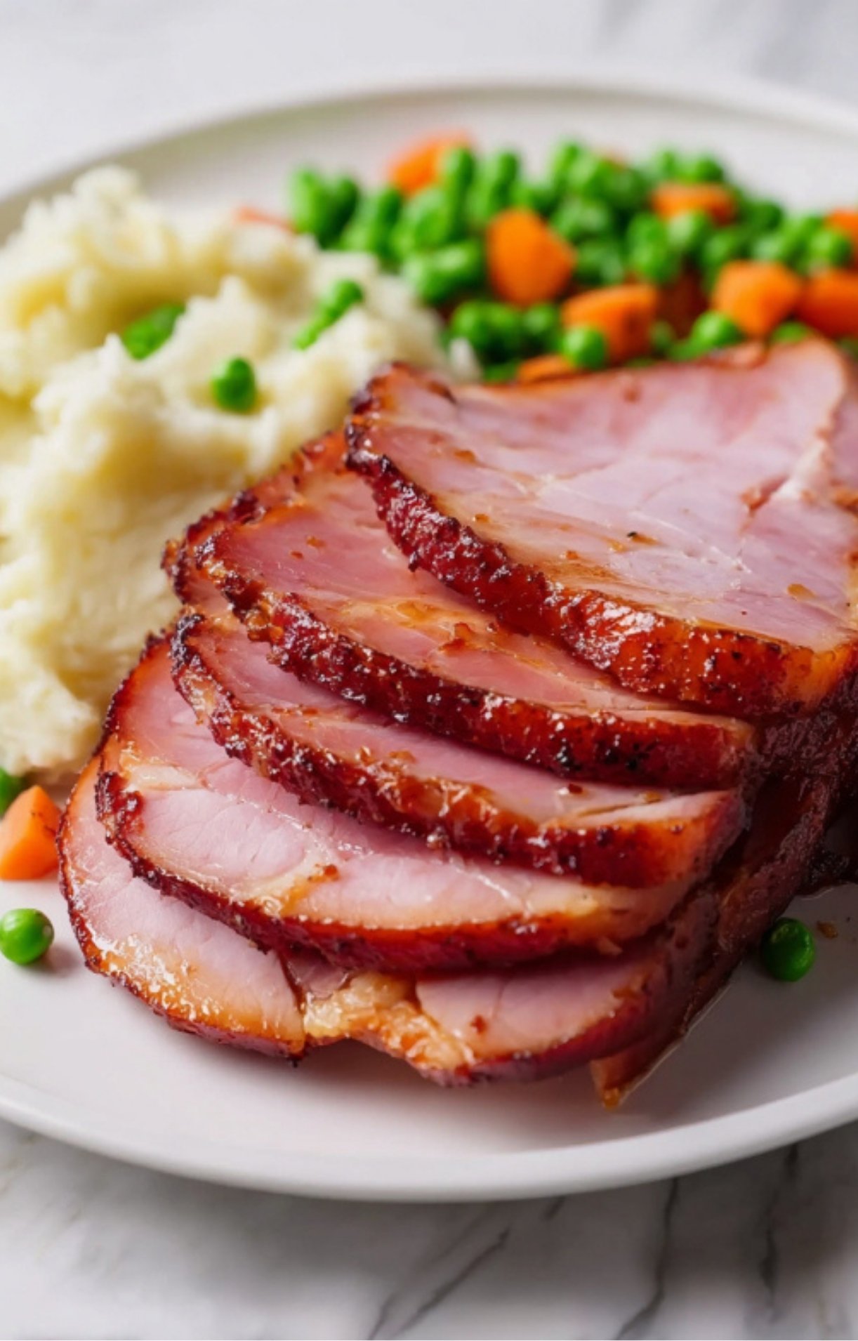 Slices of smoked ham served with mashed potatoes and mixed vegetables