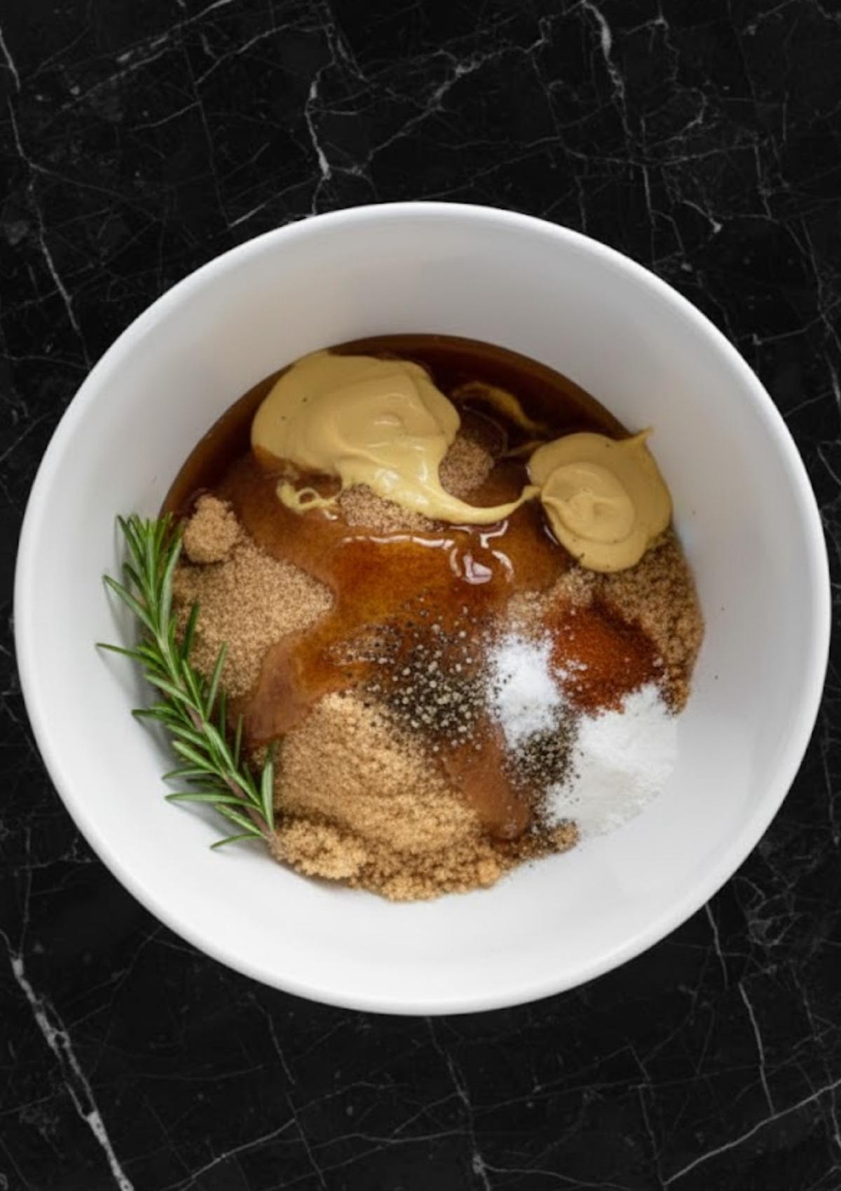 Bowl with brown sugar, maple syrup, Dijon, and rosemary for easy homemade ham glaze