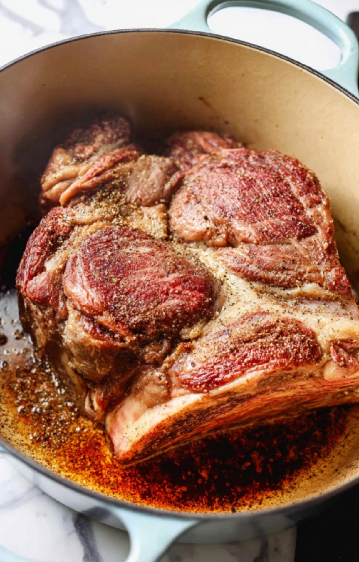 A large, seasoned beef roast browning in a blue Dutch oven to develop a deep, flavorful crust.