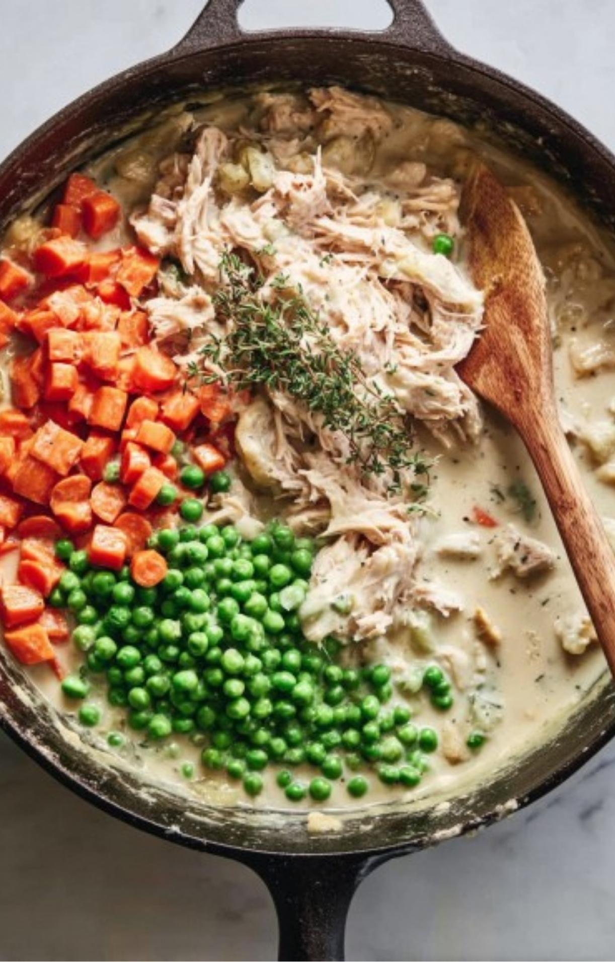 Shredded turkey, green peas, diced carrots, and fresh thyme sprigs added to the skillet before mixing.
