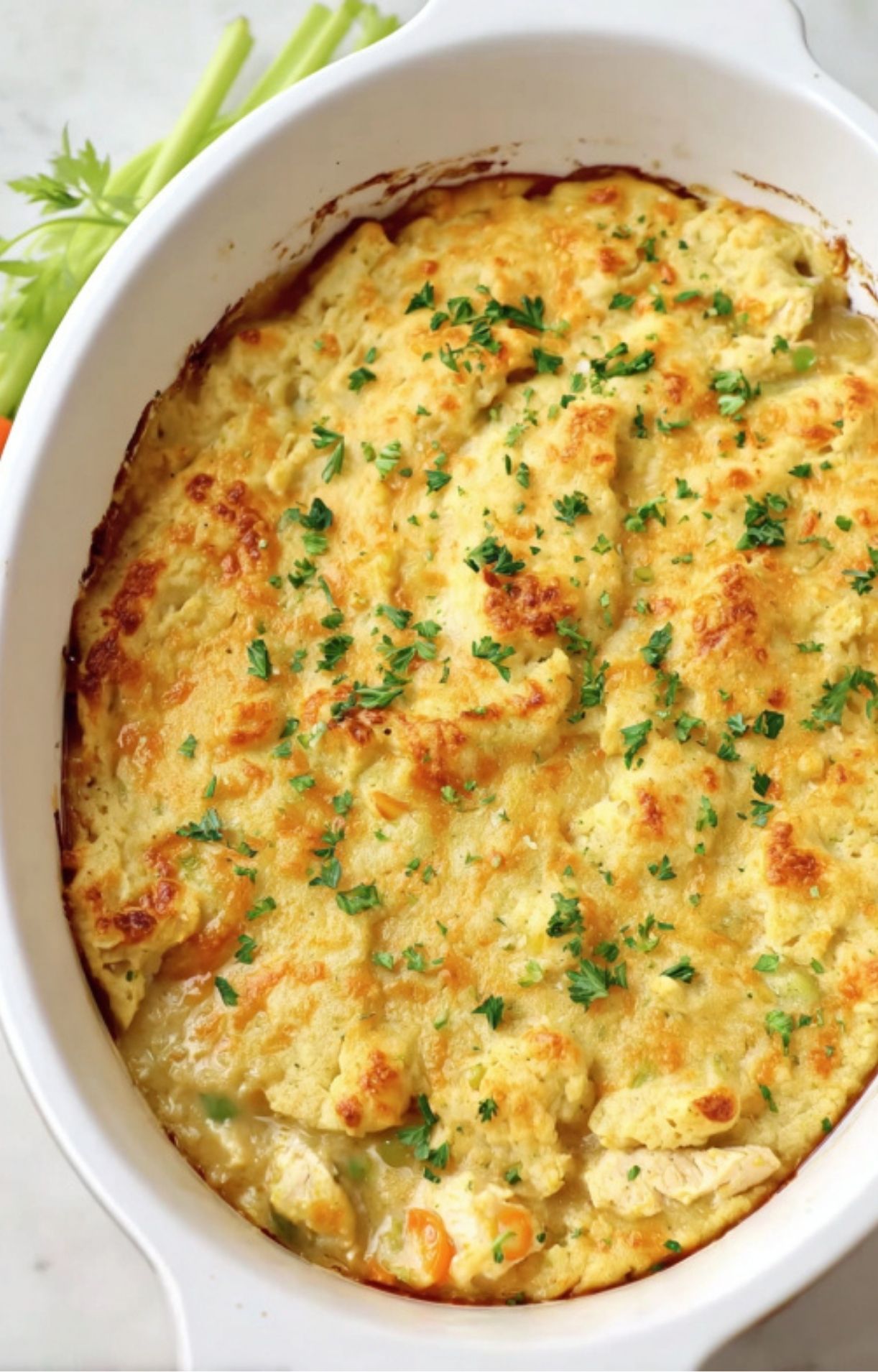 A golden-brown keto turkey pot pie straight from the oven, topped with melted cheese and a sprinkle of fresh green parsley.