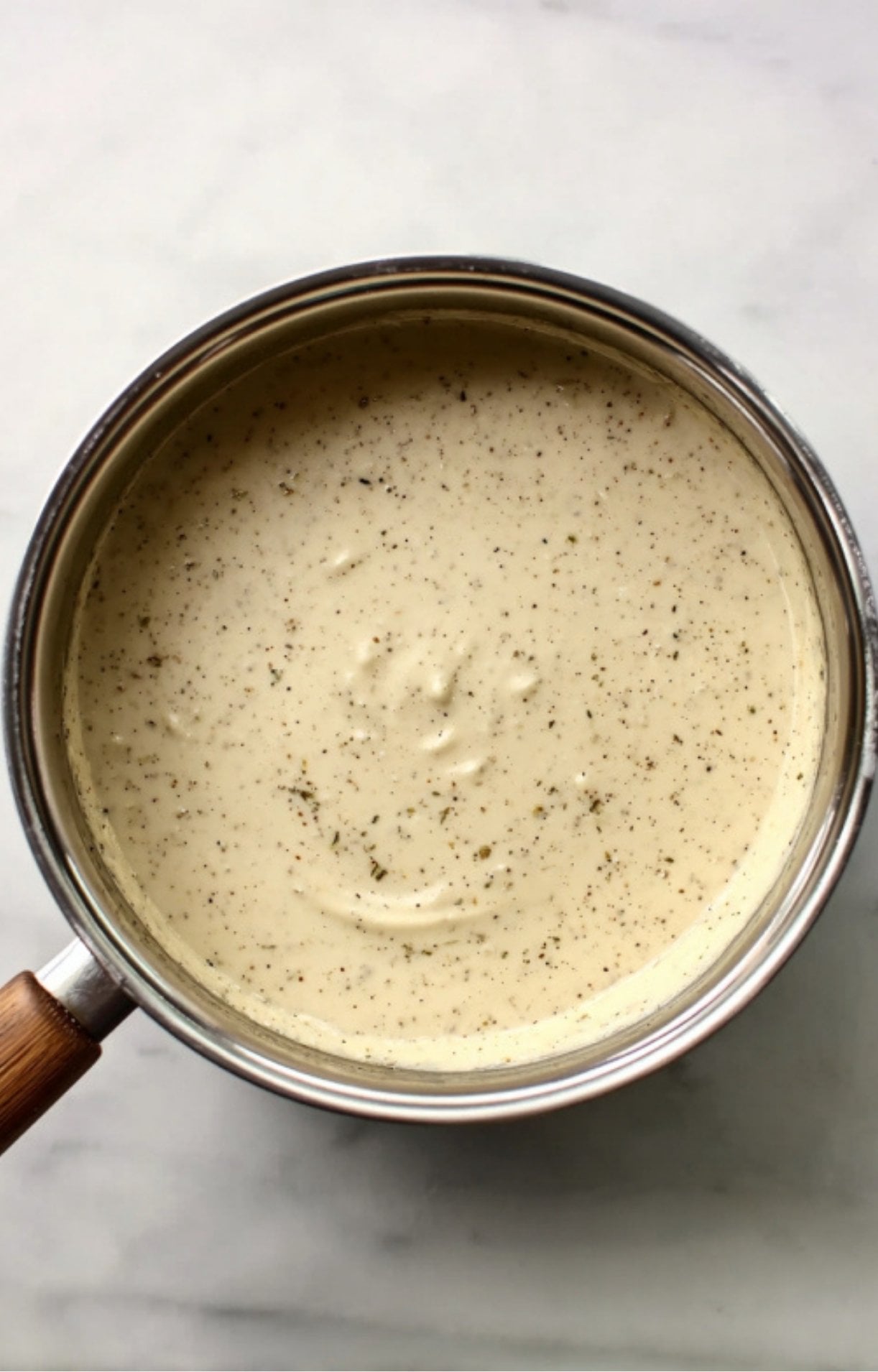 A smooth, seasoned white sauce simmering in a saucepan to create the creamy base for Dad’s Turkey Pot Pie.