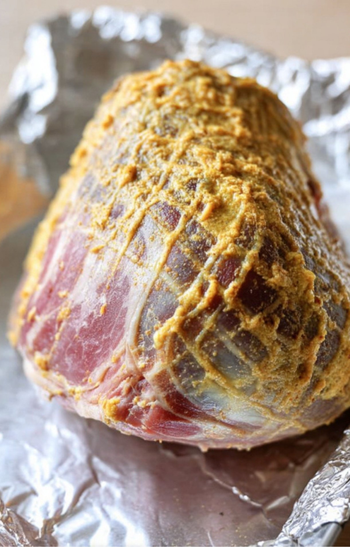 Ham covered in mustard and spice rub before smoking