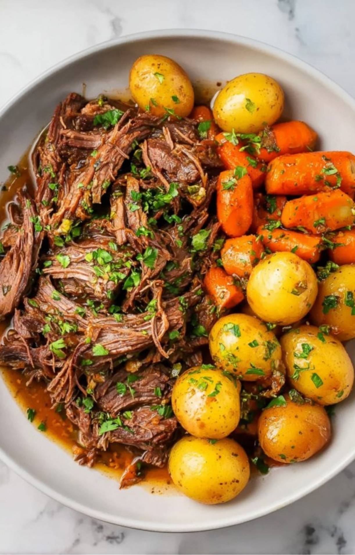 A detailed close-up of the shredded beef and vibrant orange carrots sprinkled with chopped parsley, showcasing the tender texture.