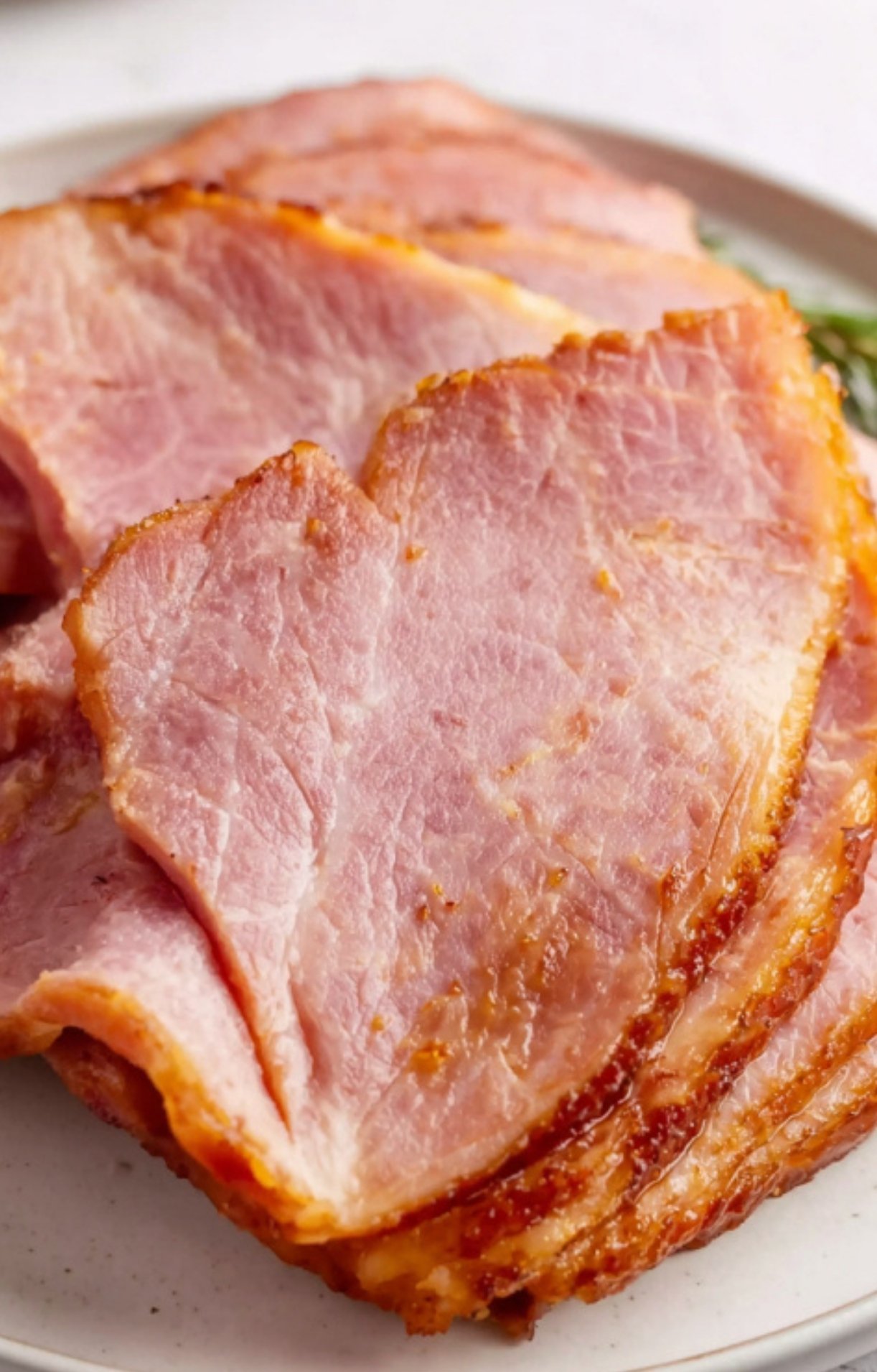Plate with juicy slices of smoked ham, pink and tender with a caramelized outer crust, perfect for family meals.