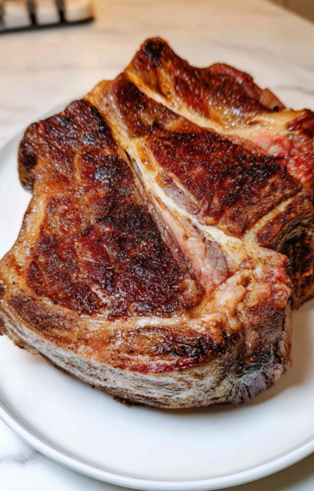 The chuck roast resting on a white plate, showing a rich, caramelized brown exterior after the initial sear.