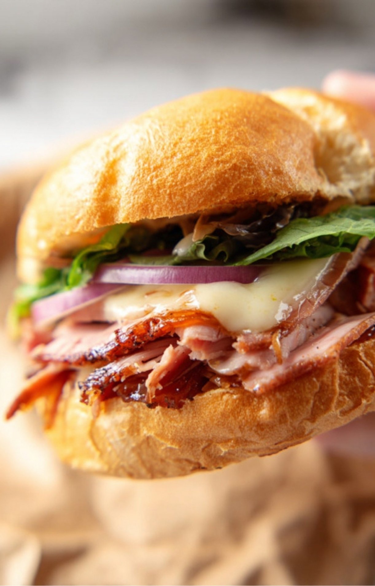 Juicy smoked pulled ham piled high on a sandwich bun with cheese and fresh toppings