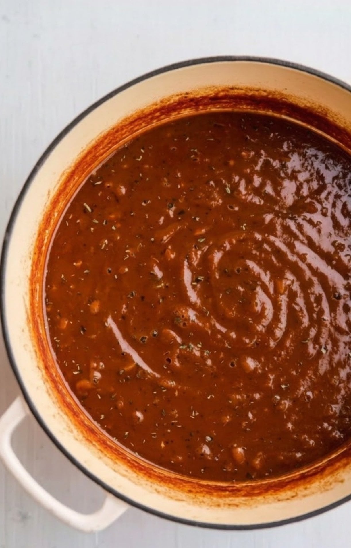 A smooth, thickened red wine reduction sauce in a pot, perfect for serving over braised beef cheeks.