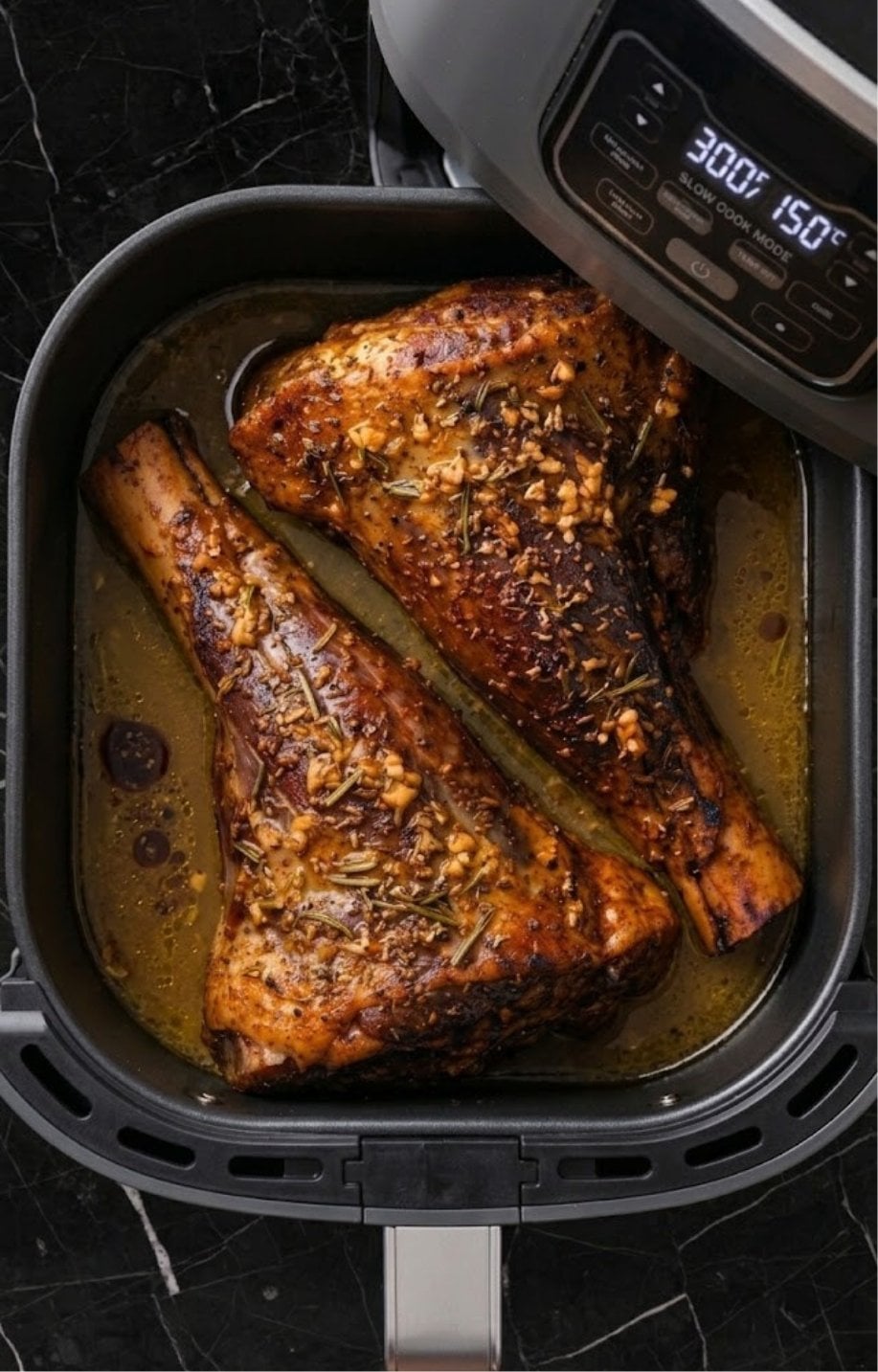 Lamb shanks submerged in a shallow broth inside the air fryer set to slow cook mode.