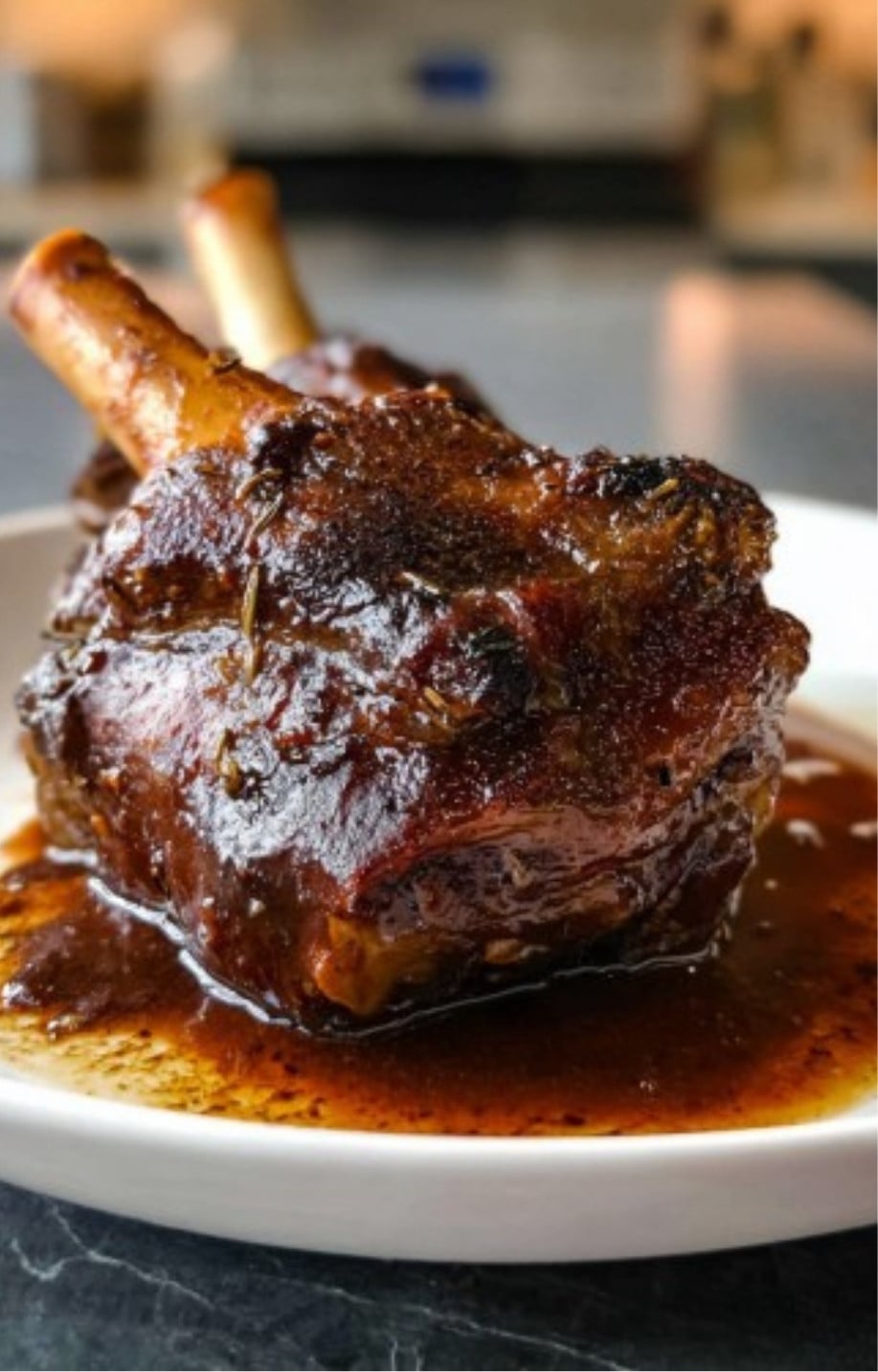 A close-up of a tender, dark-glazed lamb shank resting in a rich brown gravy.