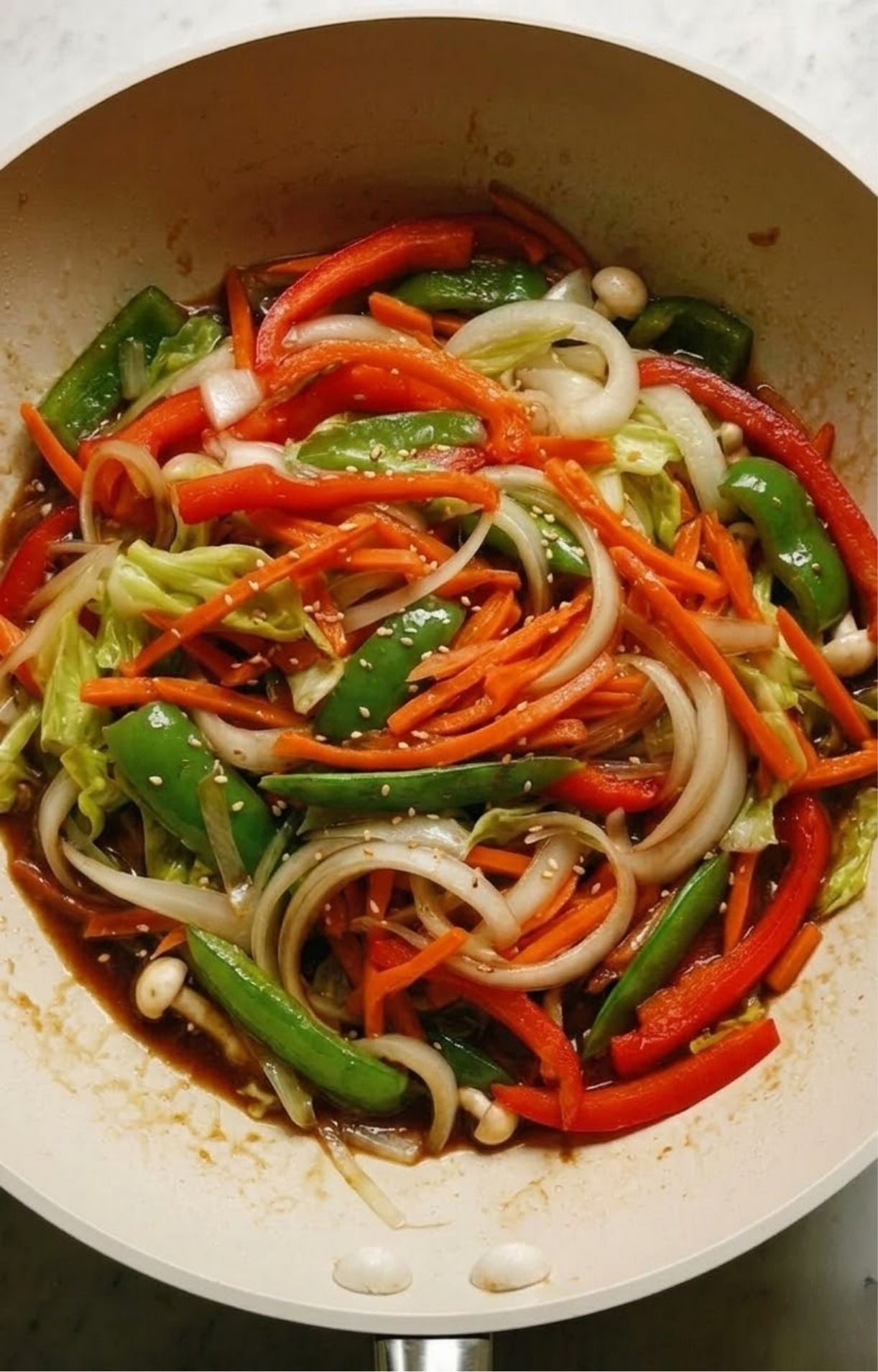 A colorful medley of peppers, onions, carrots, and mushrooms being sautéed together in a light sauce.