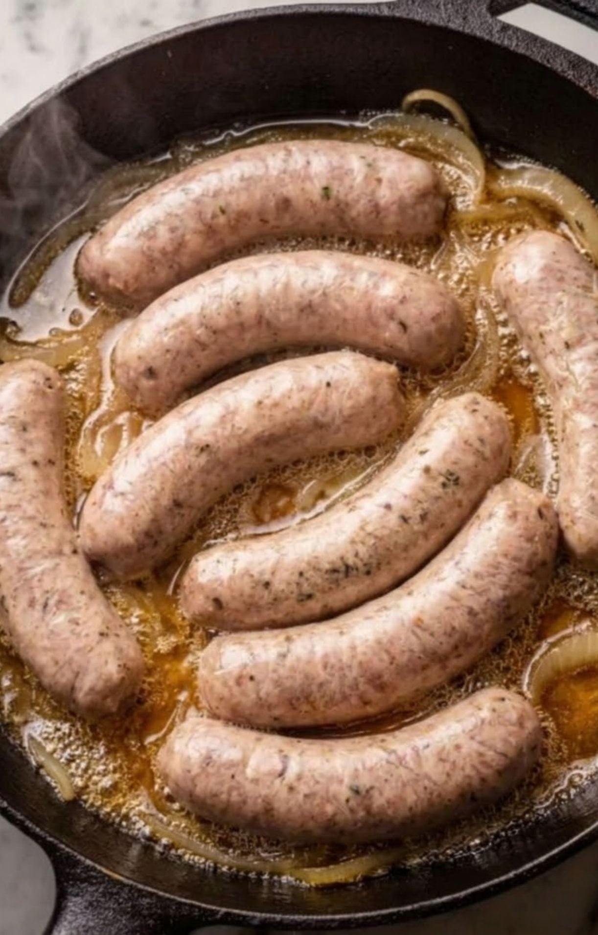 Seven bratwurst sausages simmering in a beer and onion mixture in a cast iron skillet to infuse flavor before or after air frying.