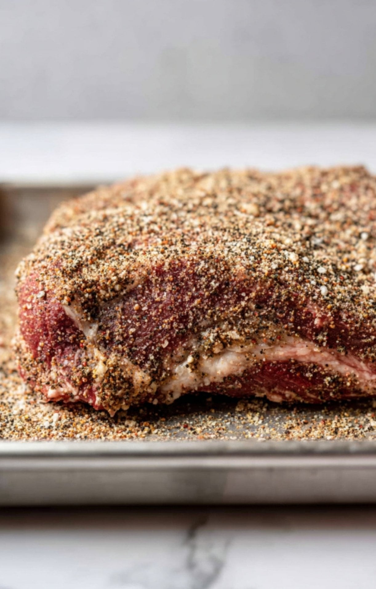 A close-up of beef brisket heavily coated in a dry rub seasoning to create flavor for Smoked Beef Brisket Burnt Ends.