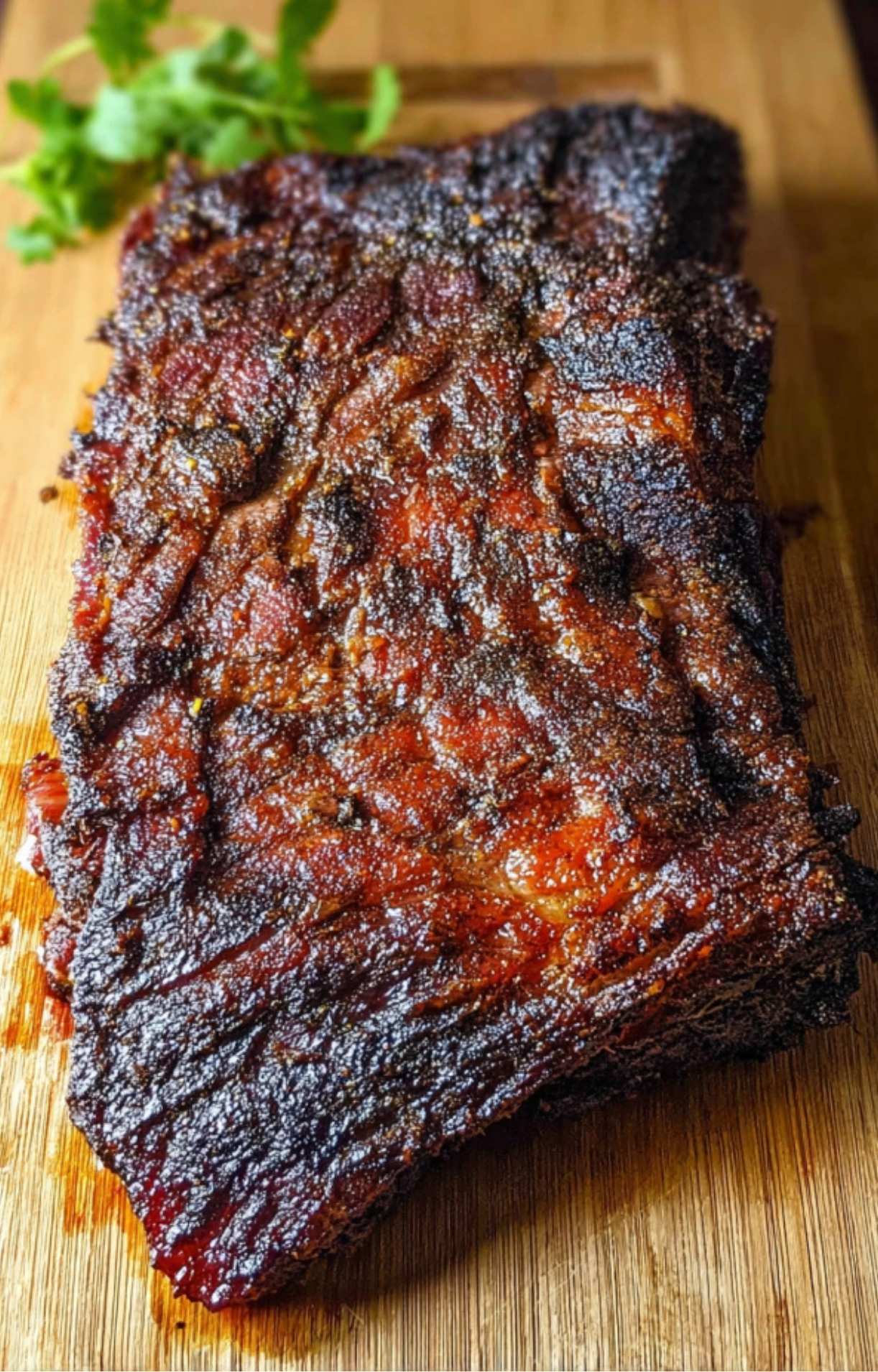 A fully smoked beef brisket with a dark, flavorful crust resting on a wooden board after cooking in an Electric Smoker Beef Brisket.