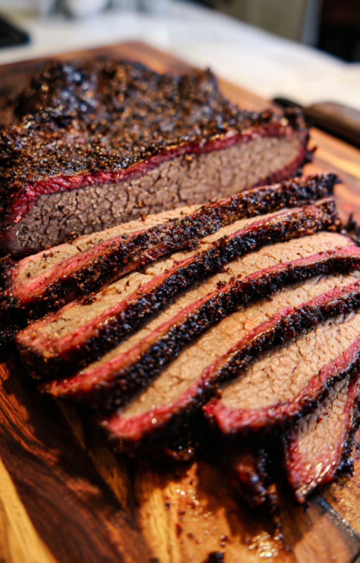 Thick, tender slices of smoked beef brisket arranged on a wooden cutting board, showcasing the internal texture and smoke ring.