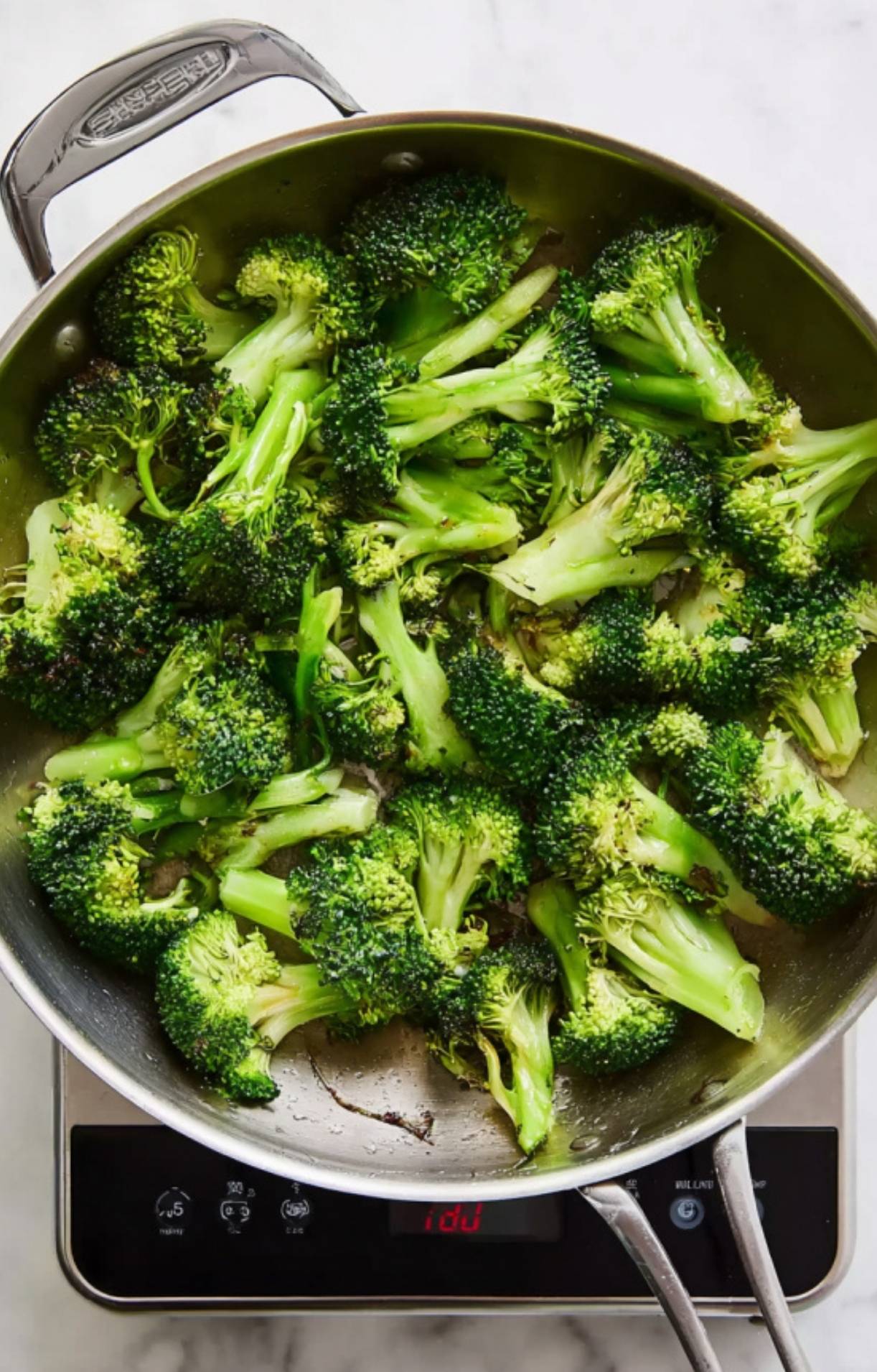 Fresh broccoli florets being lightly seared in a hot pan as a preparatory step for Beijing beef and broccoli.