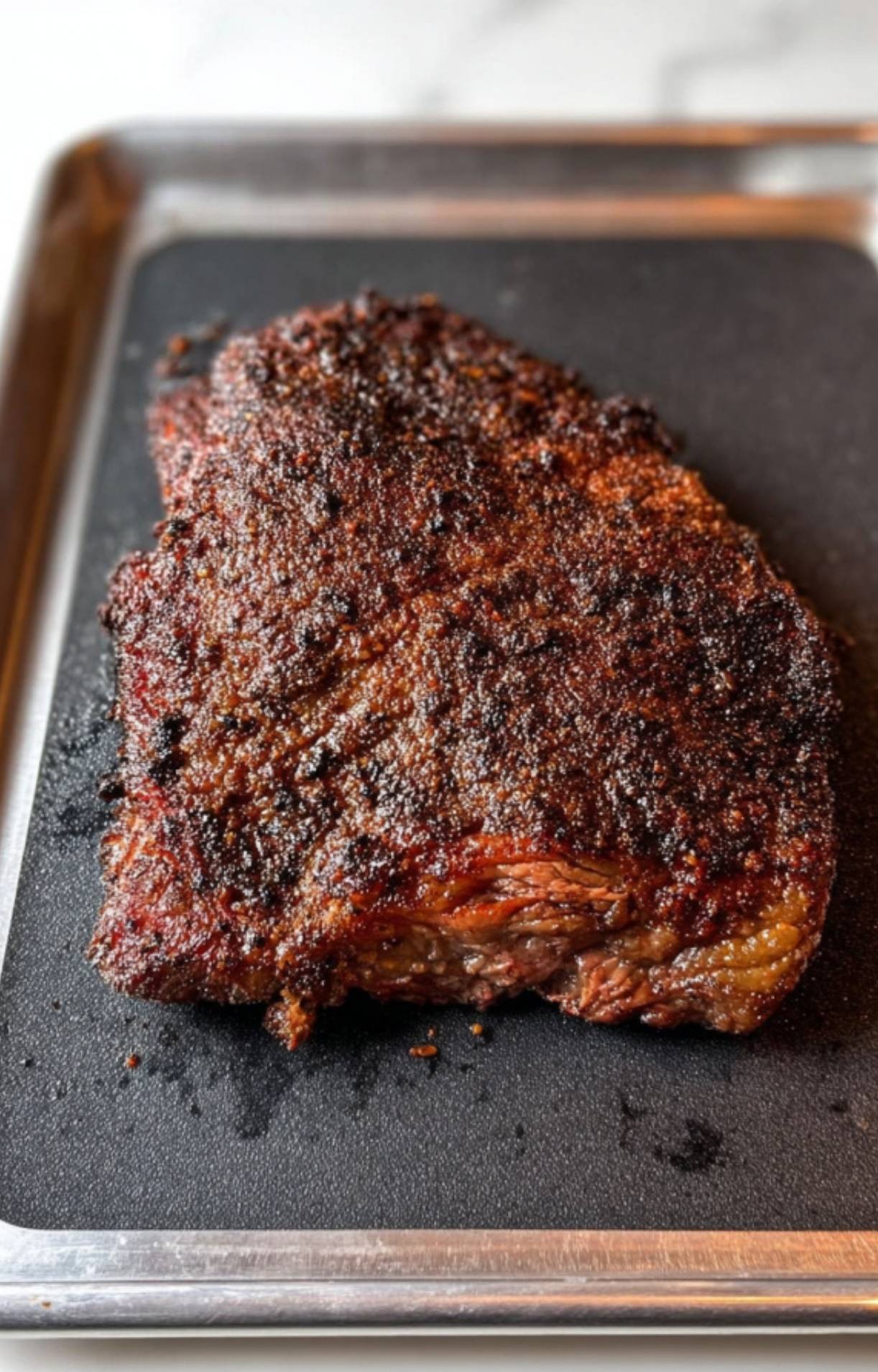 A whole smoked beef brisket with a dark, crusty bark sitting on a tray before being cut into Smoked Beef Brisket Burnt Ends.