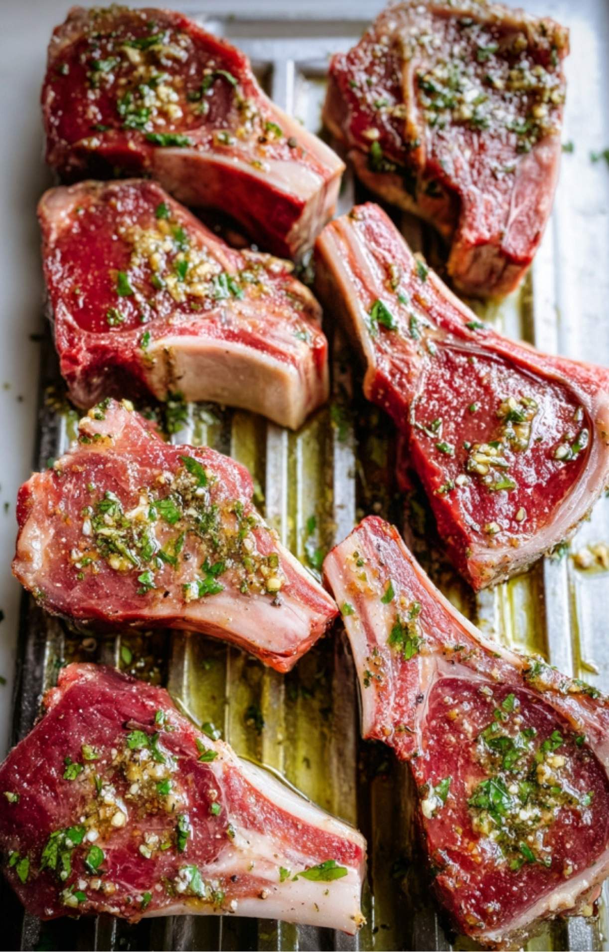 Seasoned raw lamb loin chops arranged in a single layer on a metal air fryer rack, ready to be cooked.