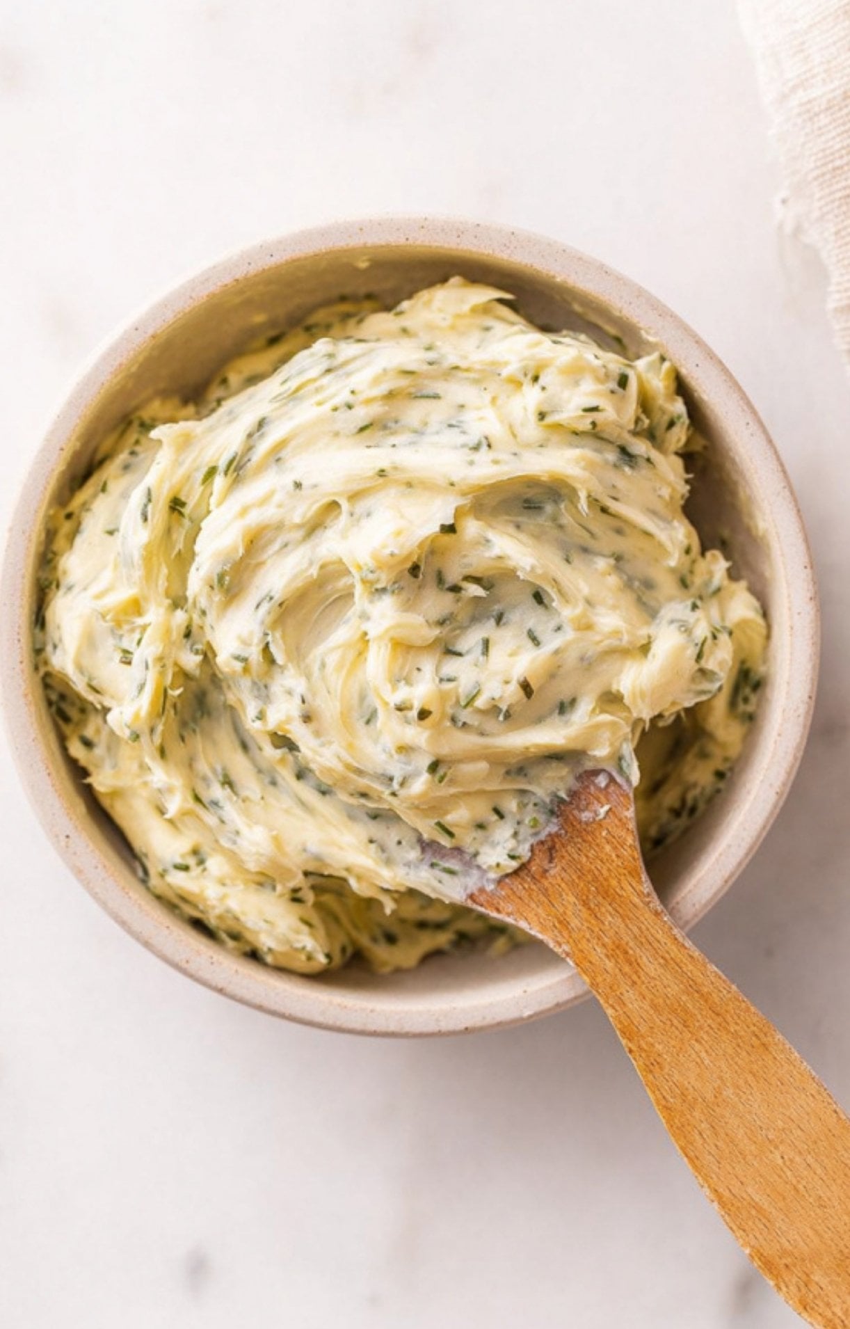 A bowl of creamy compound garlic and herb butter for topping a smoked tomahawk steak.