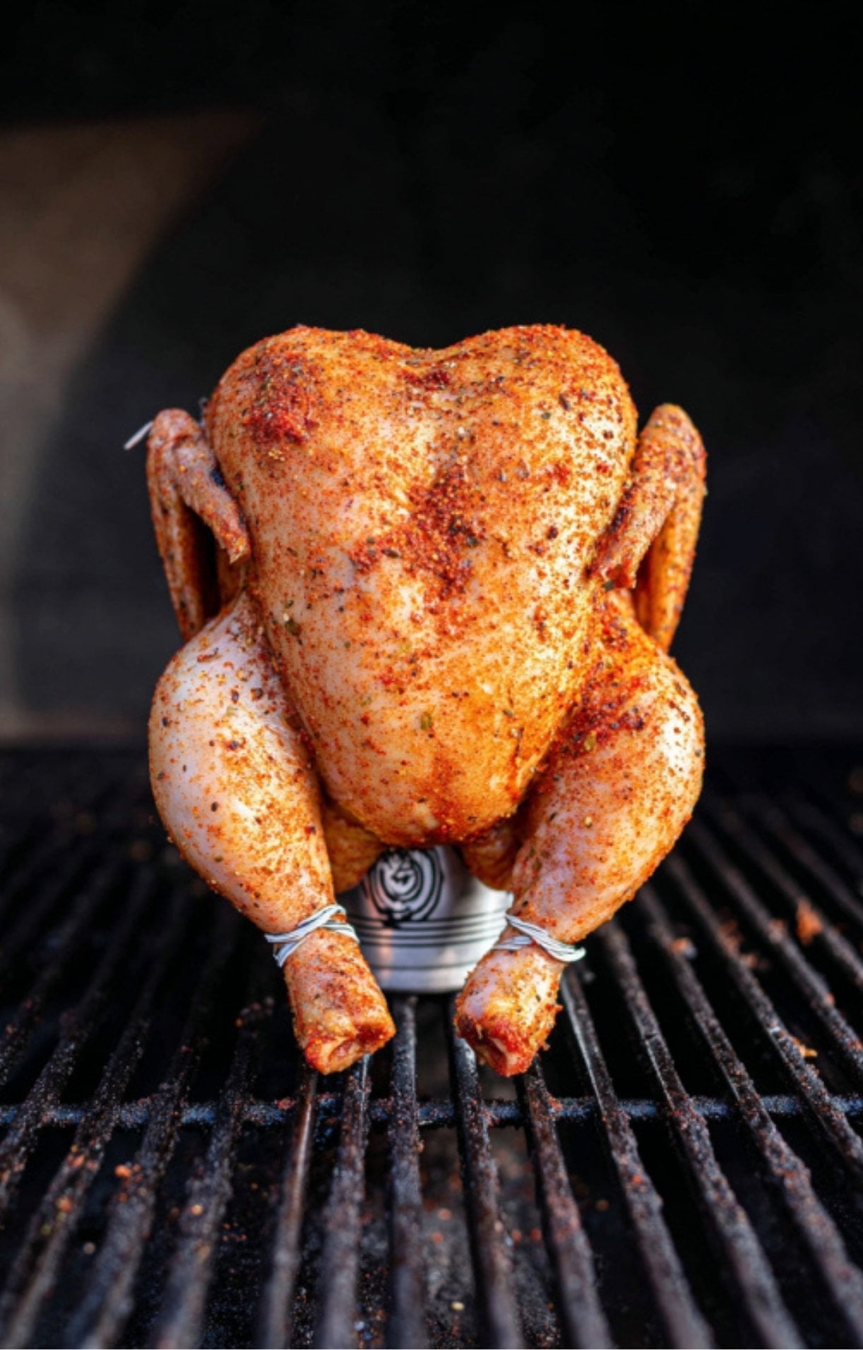 A wide shot of a rub-coated chicken placed on the grill grates, highlighting the start of the smoking process.