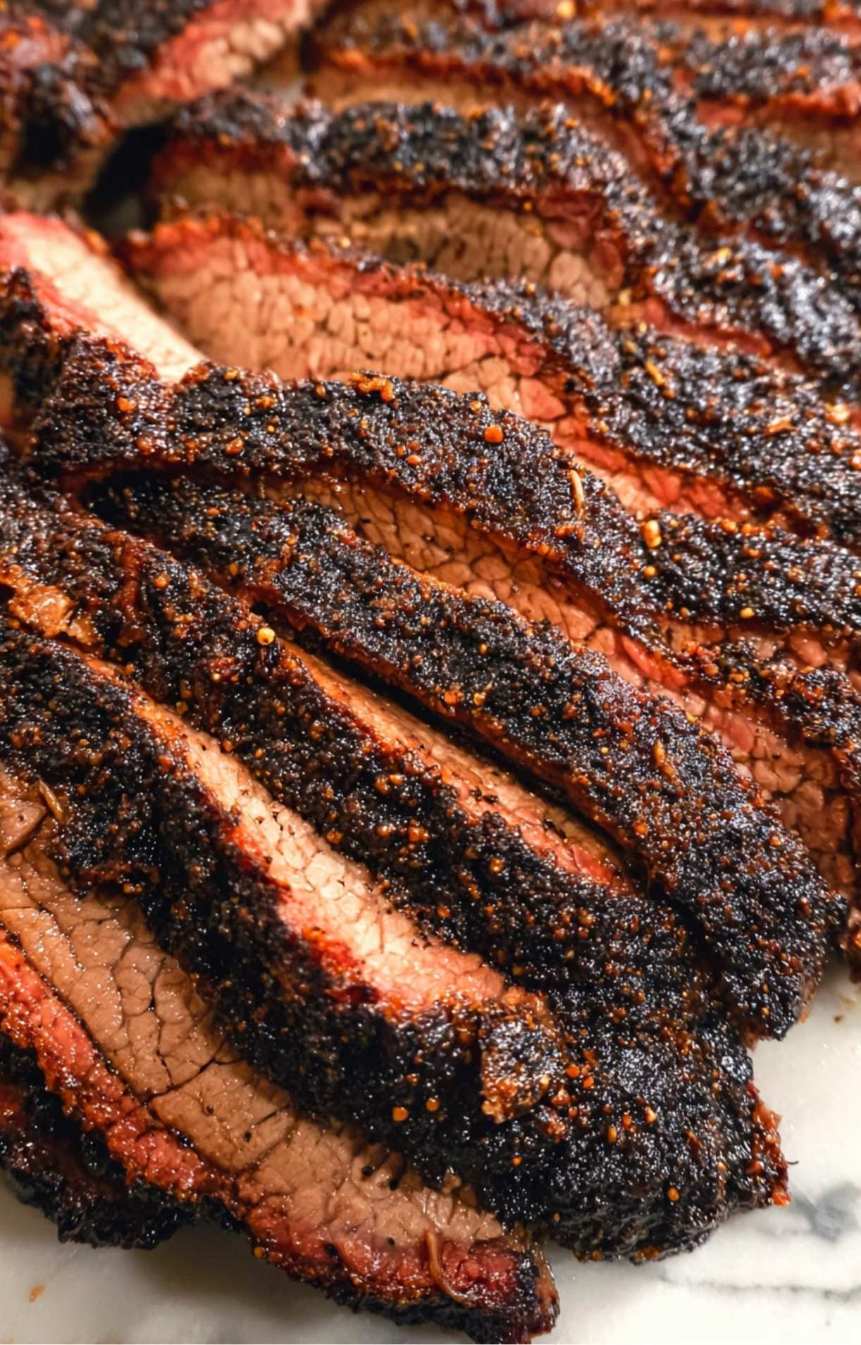 Macro shot of thick, juicy slices of brisket showcasing the dark crust and tender meat fibers.
