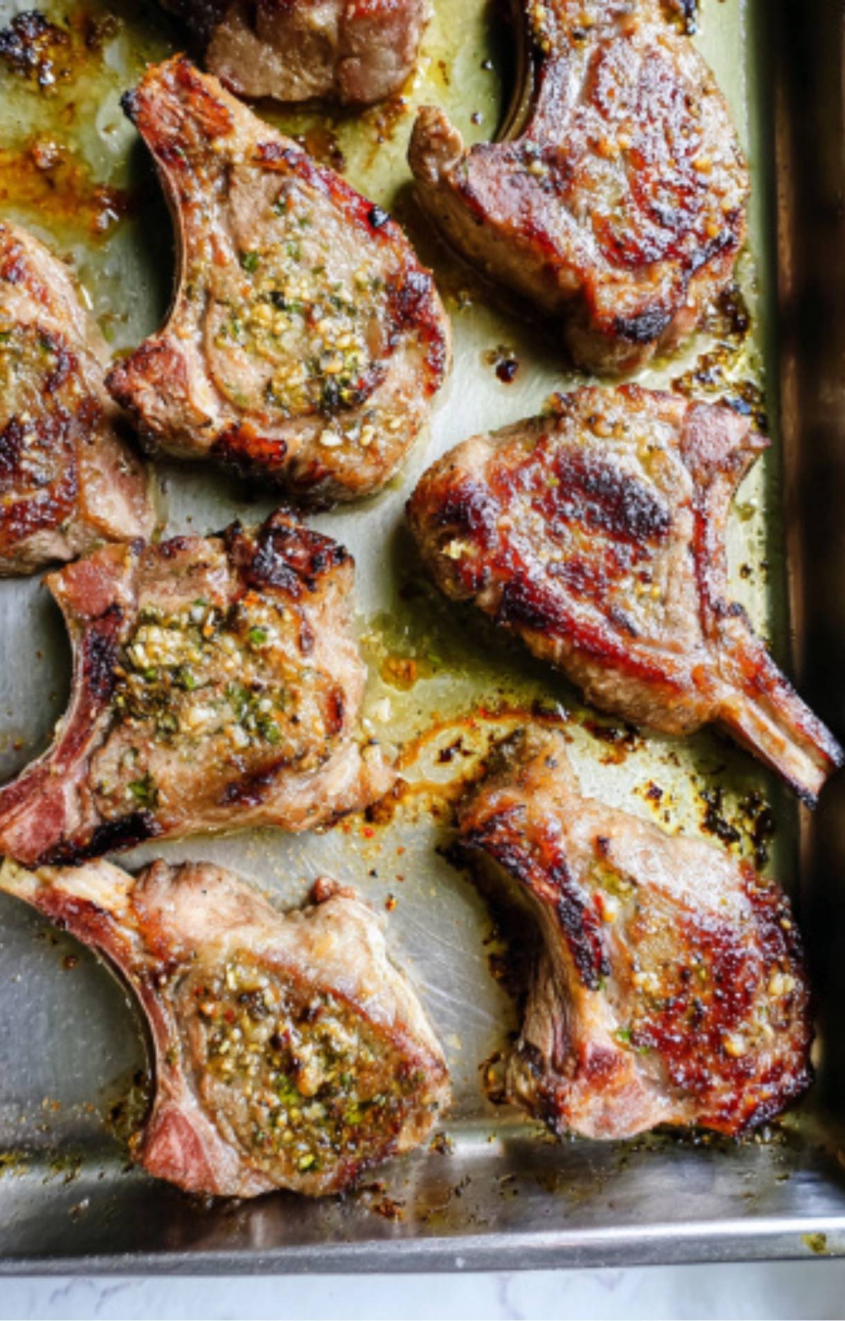 Golden brown, sizzled lamb loin chops sitting in a metal baking pan immediately after being air fried.