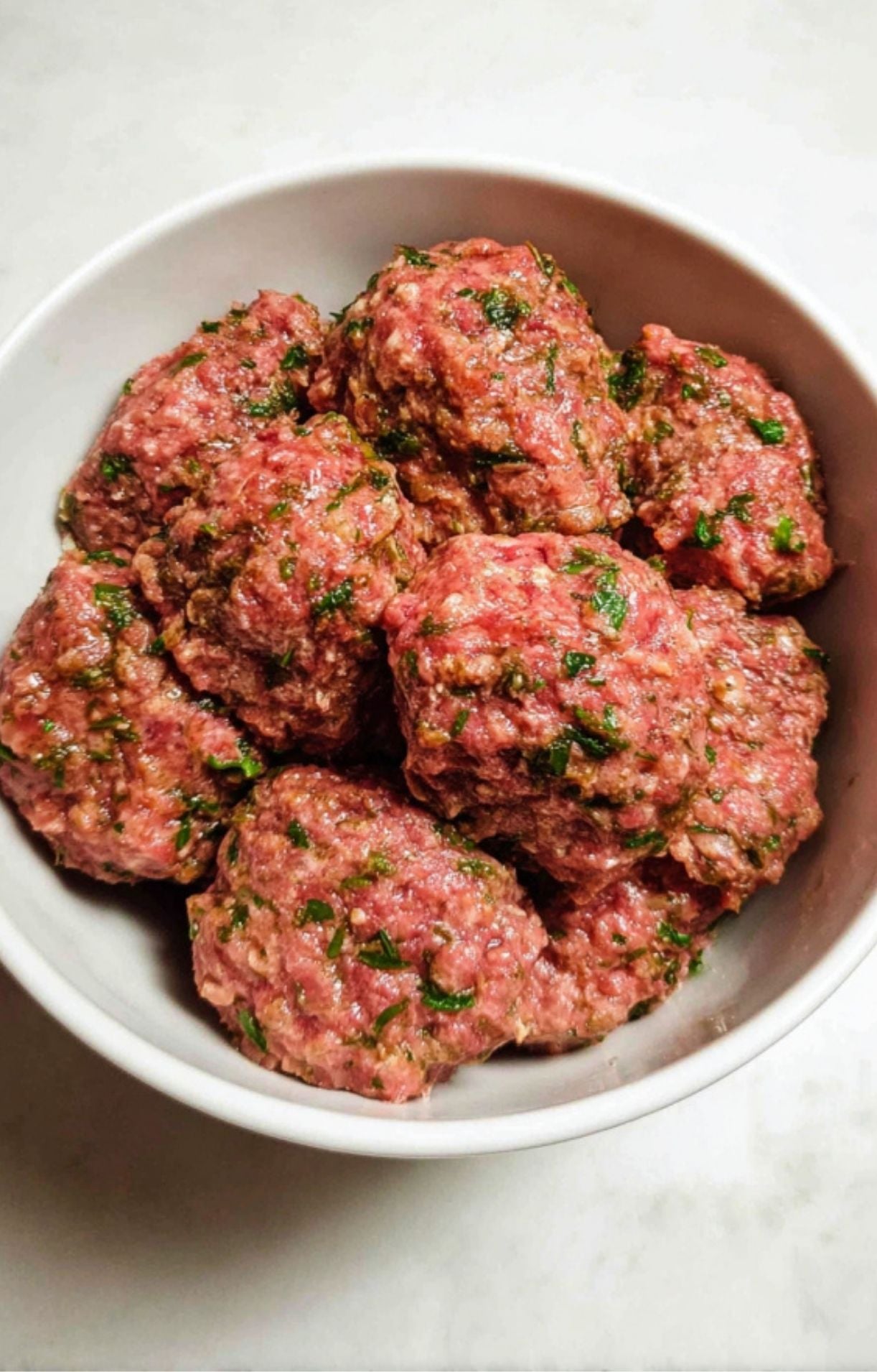 A bowl showing the ground lamb and herb mixture thoroughly combined and ready to be shaped.