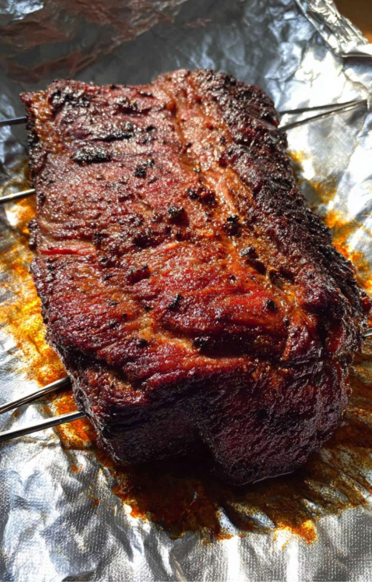 A hot, smoked beef brisket resting inside open foil, showing its juicy texture after being cooked as an Electric Smoker Beef Brisket.