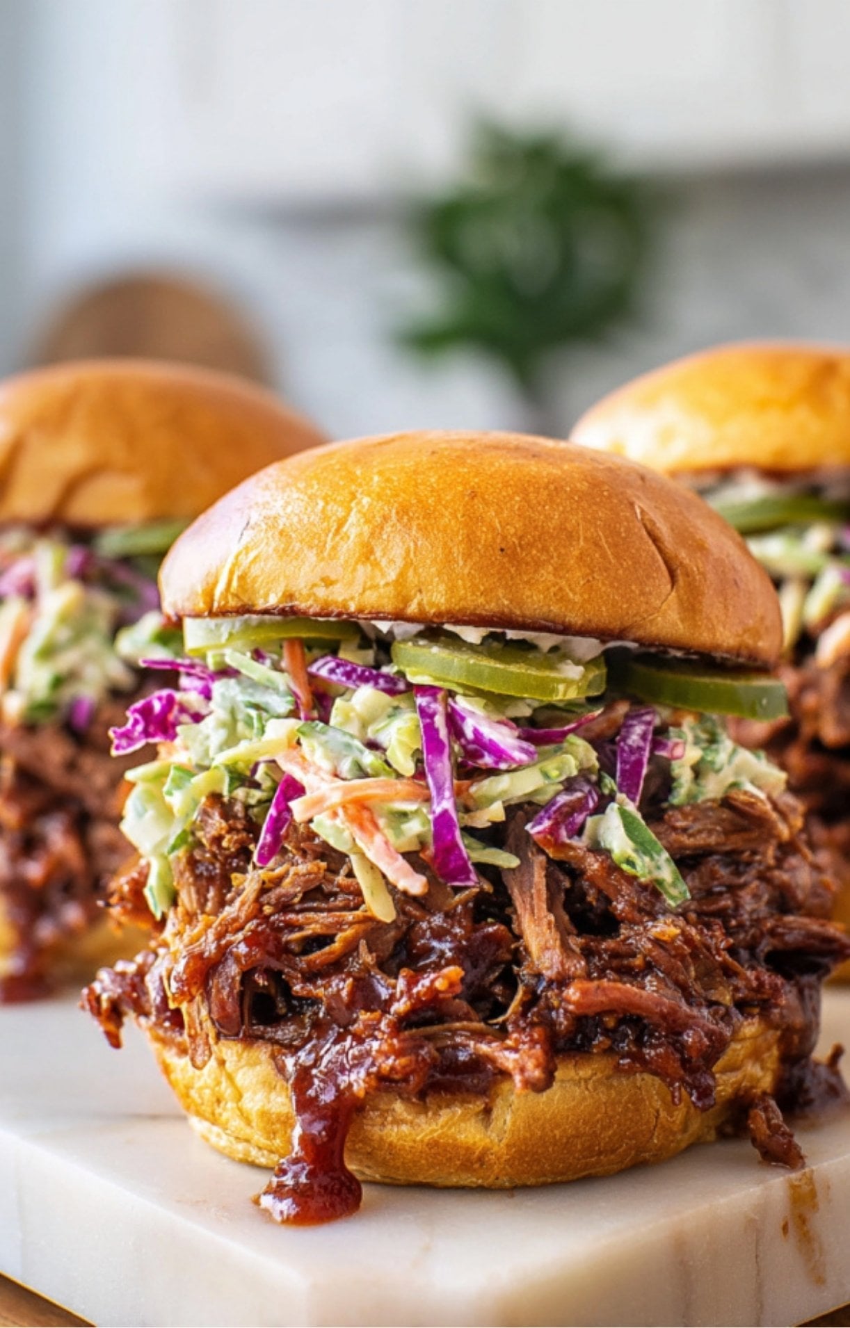 Multiple Easy Smoked Brisket Sandwiches arranged on a white marble surface, showcasing the vibrant purple cabbage in the slaw.