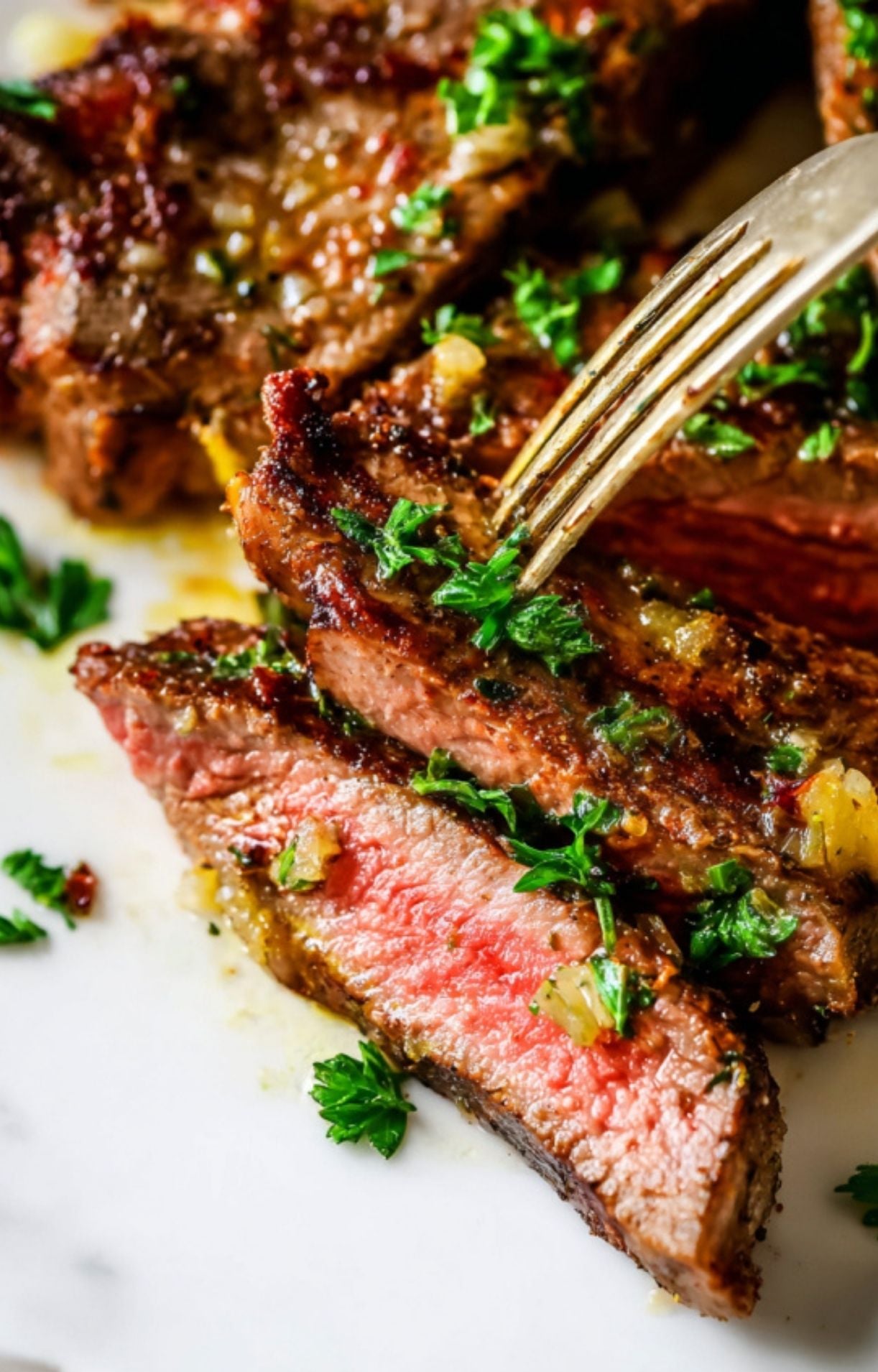 A close-up shot of a juicy lamb loin chop sliced into sections, revealing a perfect pink medium-rare center and topped with fresh parsley.