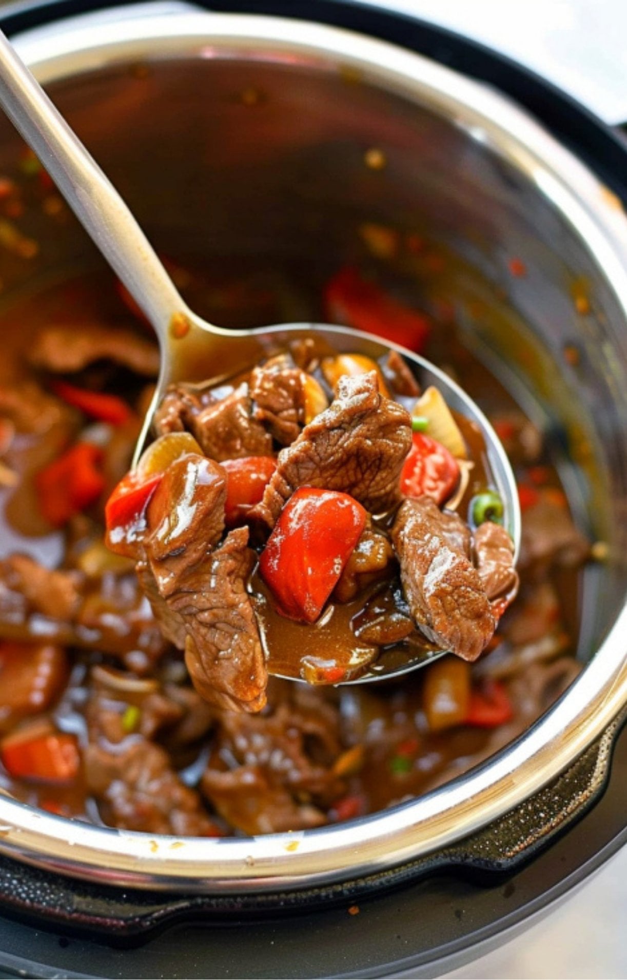 A large metal ladle scoops a serving of Beijing beef, showcasing chunks of meat and red bell peppers dripping with thick brown sauce directly from an Instant Pot inner liner.