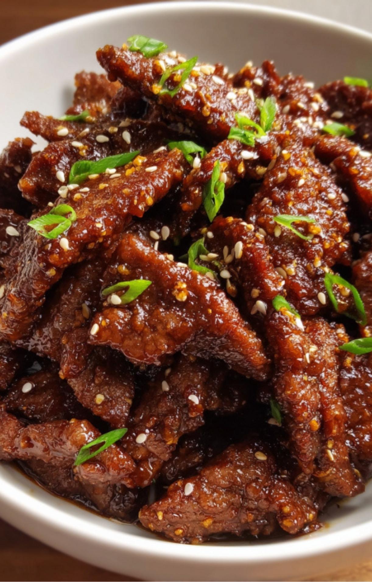 A high-detail view of the textured, saucy beef strips highlighting the sesame seed and scallion garnish.