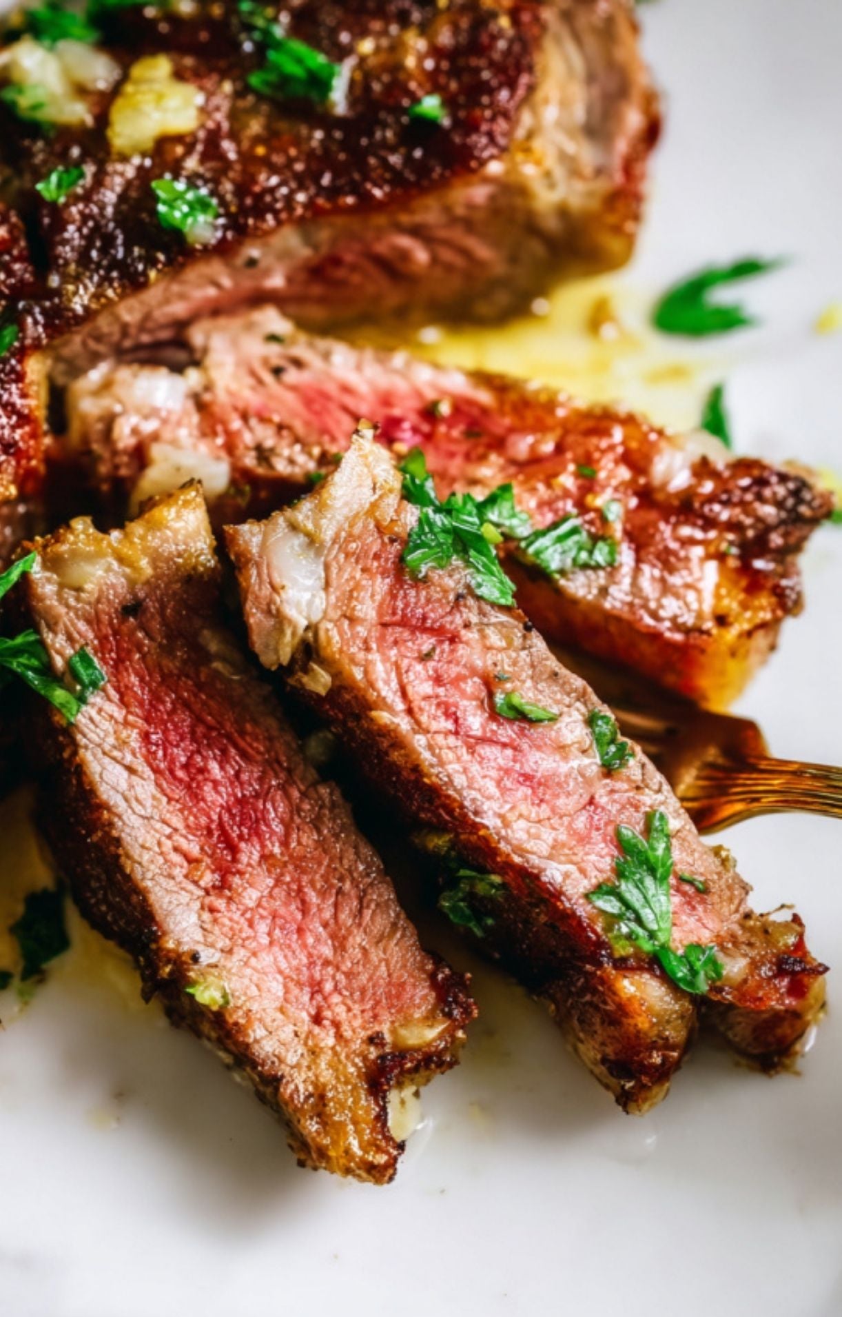 Macro view of sliced lamb loin chops on a white marble board, highlighting the tender texture and seared herb crust.