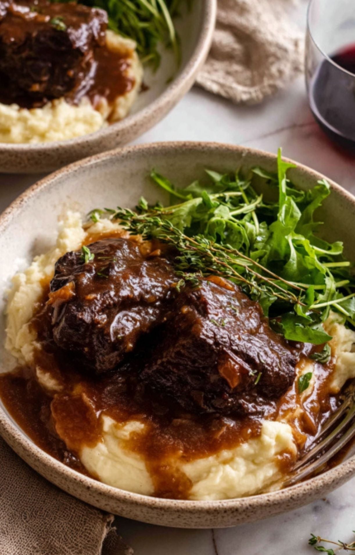 Tender, braised Spanish beef cheeks served over creamy mashed potatoes, garnished with fresh thyme and a side of green salad.