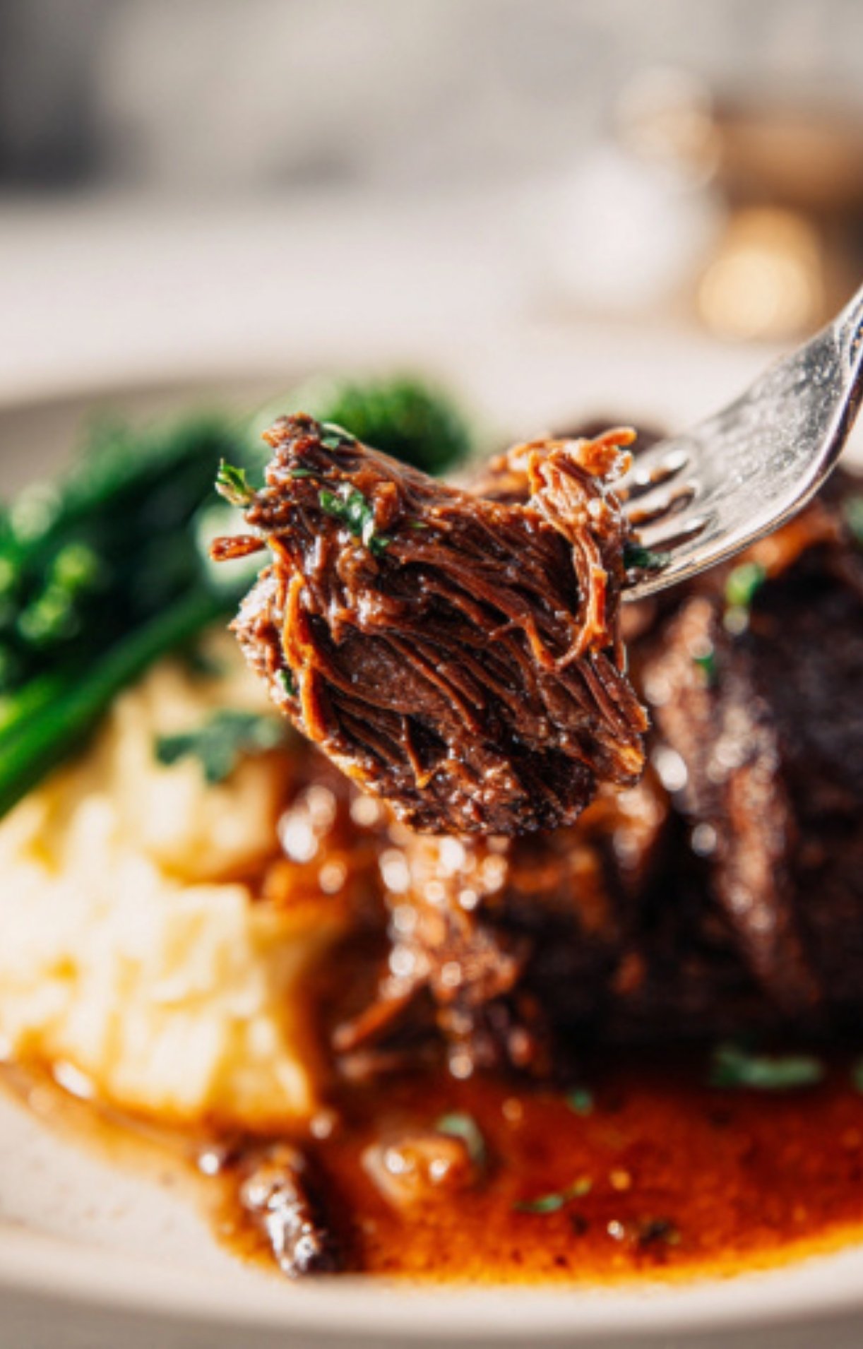 A close-up of a fork lifting a piece of shredded, succulent meat from a finished Wagyu Beef Cheeks Recipe, showing the tender texture.