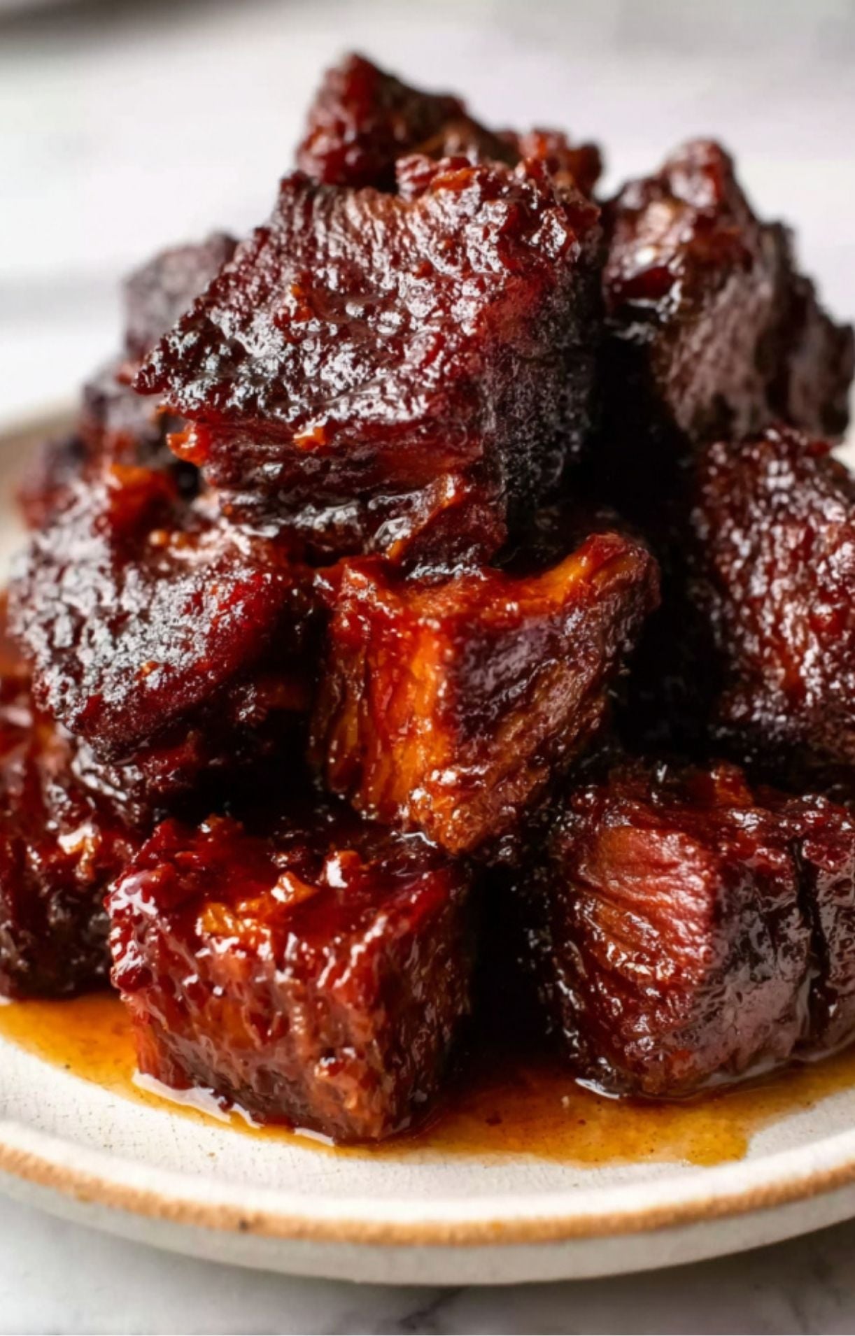 A close-up stack of shiny, sauce-covered Smoked Beef Brisket Burnt Ends on a plate, highlighting the rich, caramelized exterior.