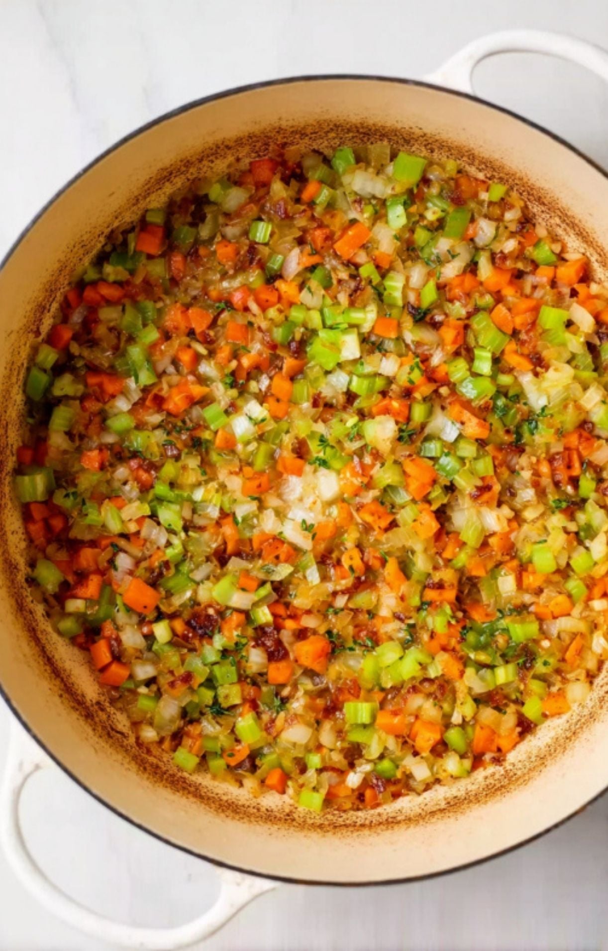 Finely diced carrots, celery, and onions softening in a Dutch oven as a base for braised beef cheeks.