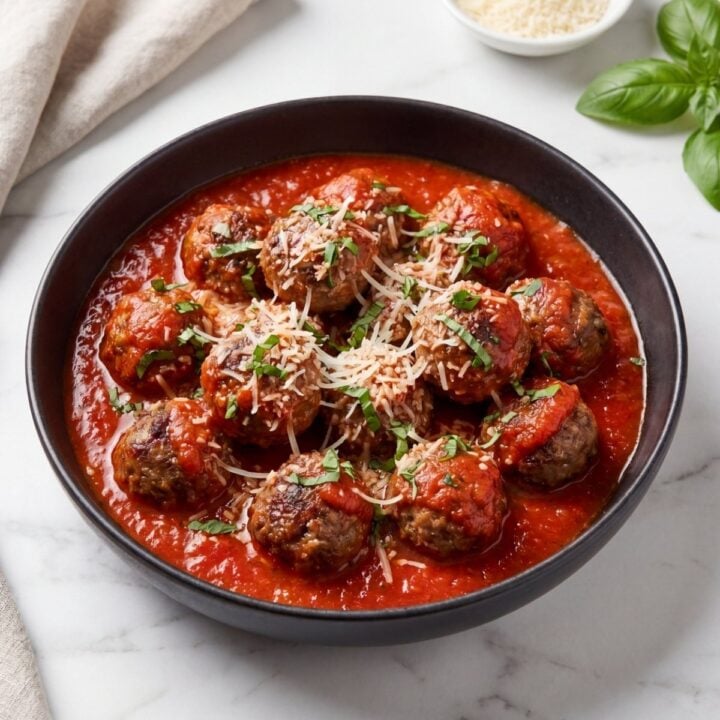 close up wagyu beef meatballs with marinara sauce parmesan cheese and basil garnish