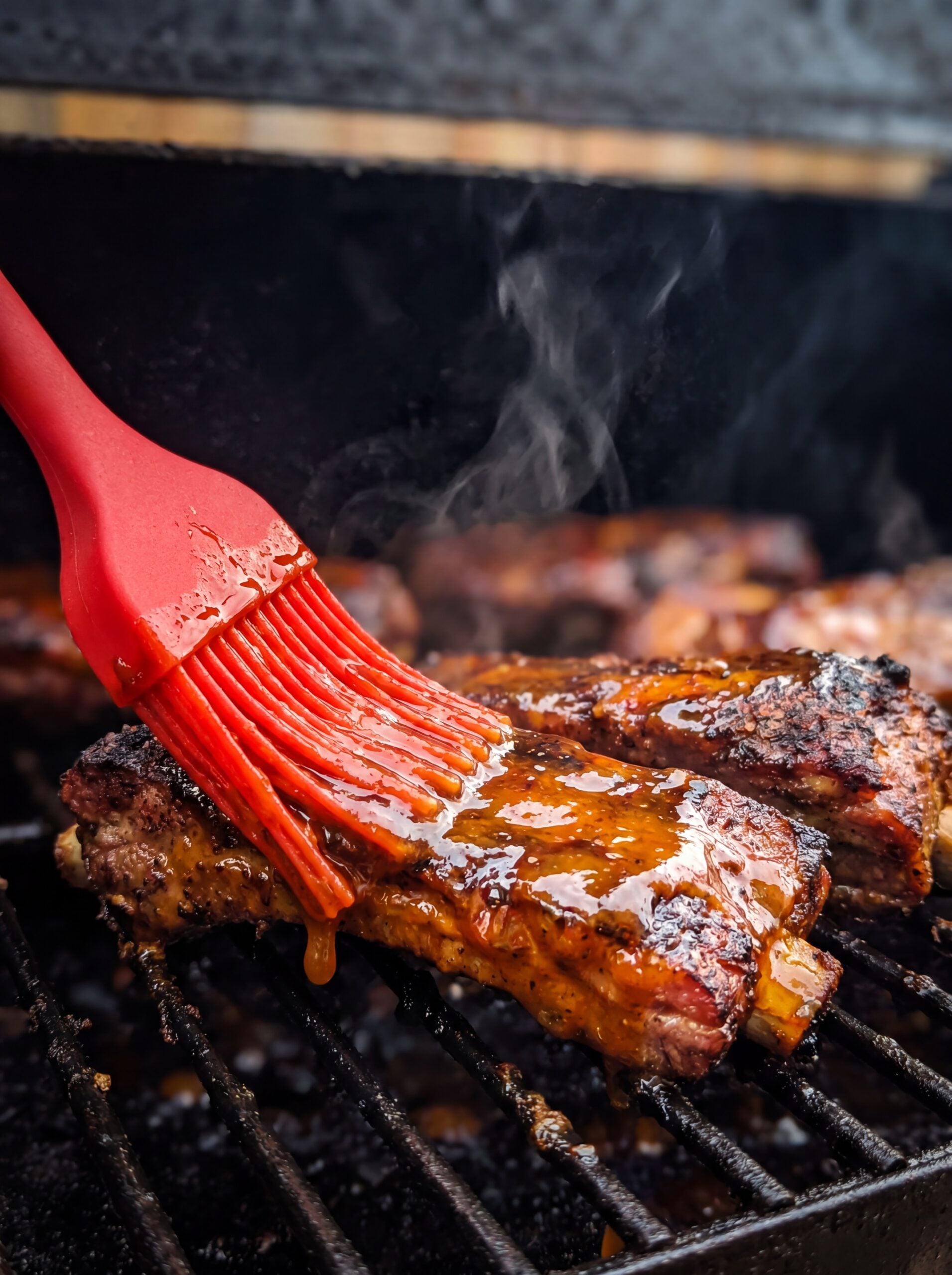 brushing bbq sauce on ribs during pellet smoker cooking process