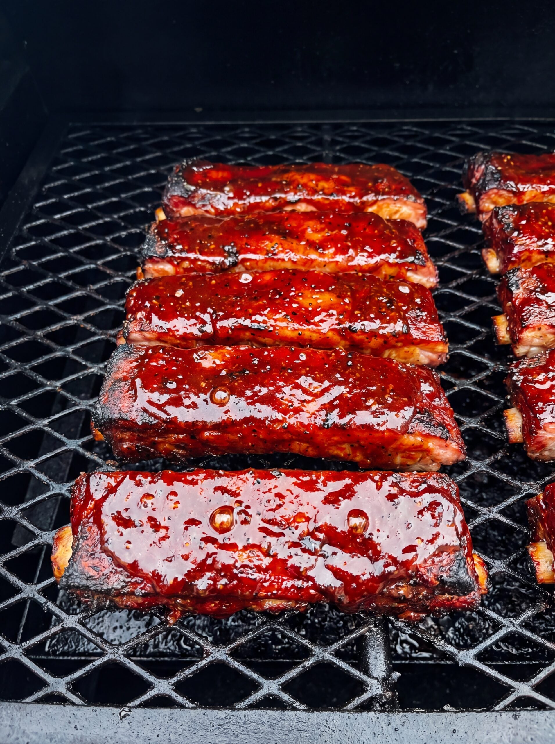 glazed country style ribs on smoker with shiny bbq sauce finish