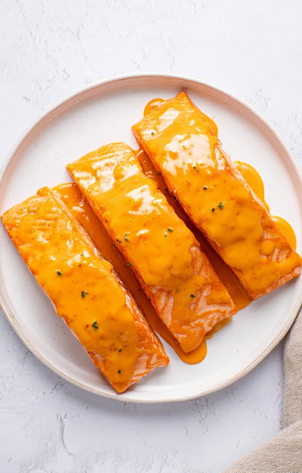 Three raw salmon fillets covered in a thick, orange Bang Bang marinade.