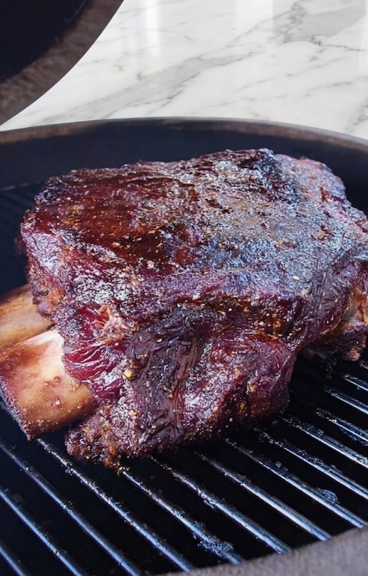 Beef short ribs cooking on pellet smoker grill with seasoning and smoke
