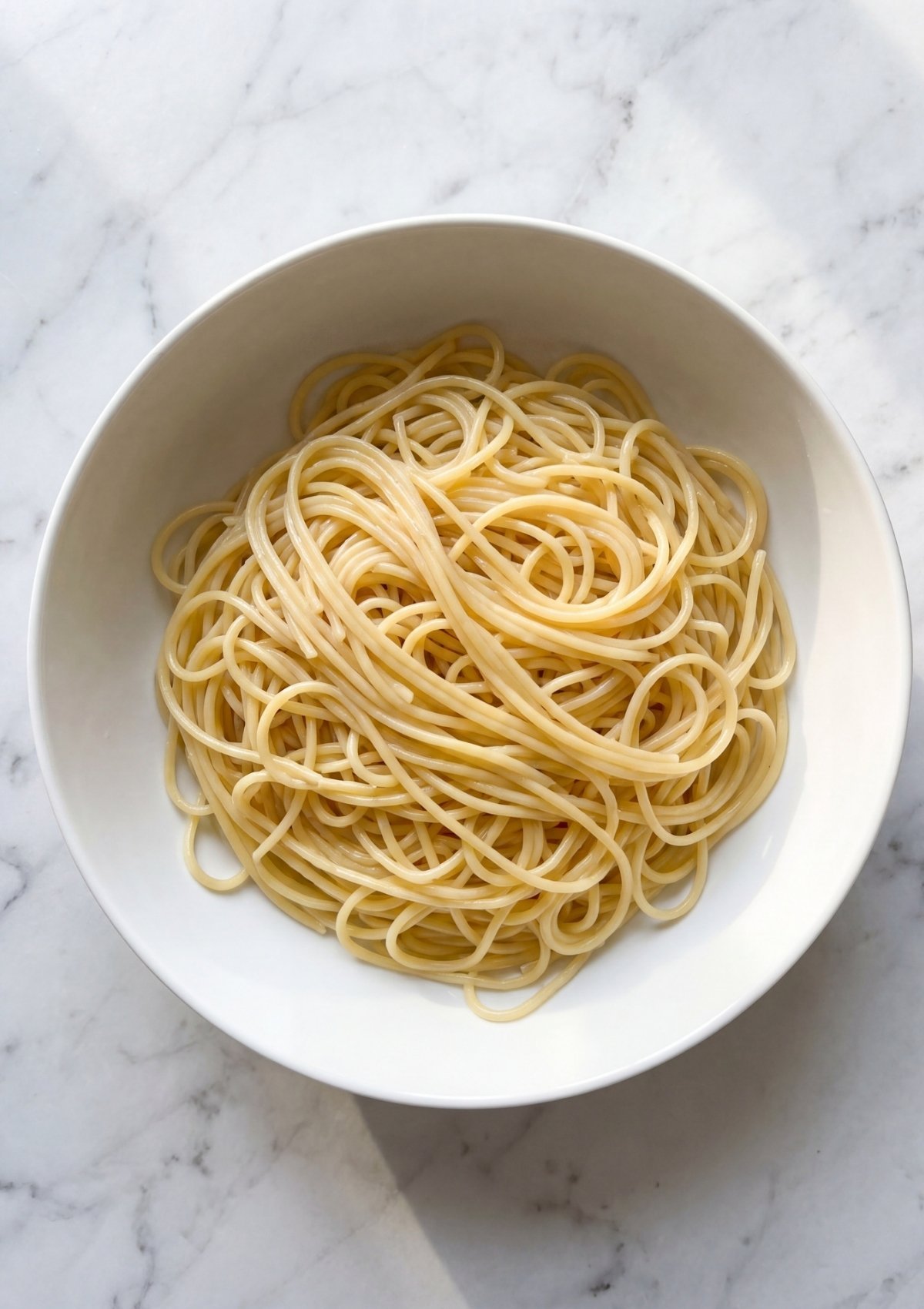 plain cooked spaghetti noodles in bowl ready for cowboy spaghetti with bacon recipe prep